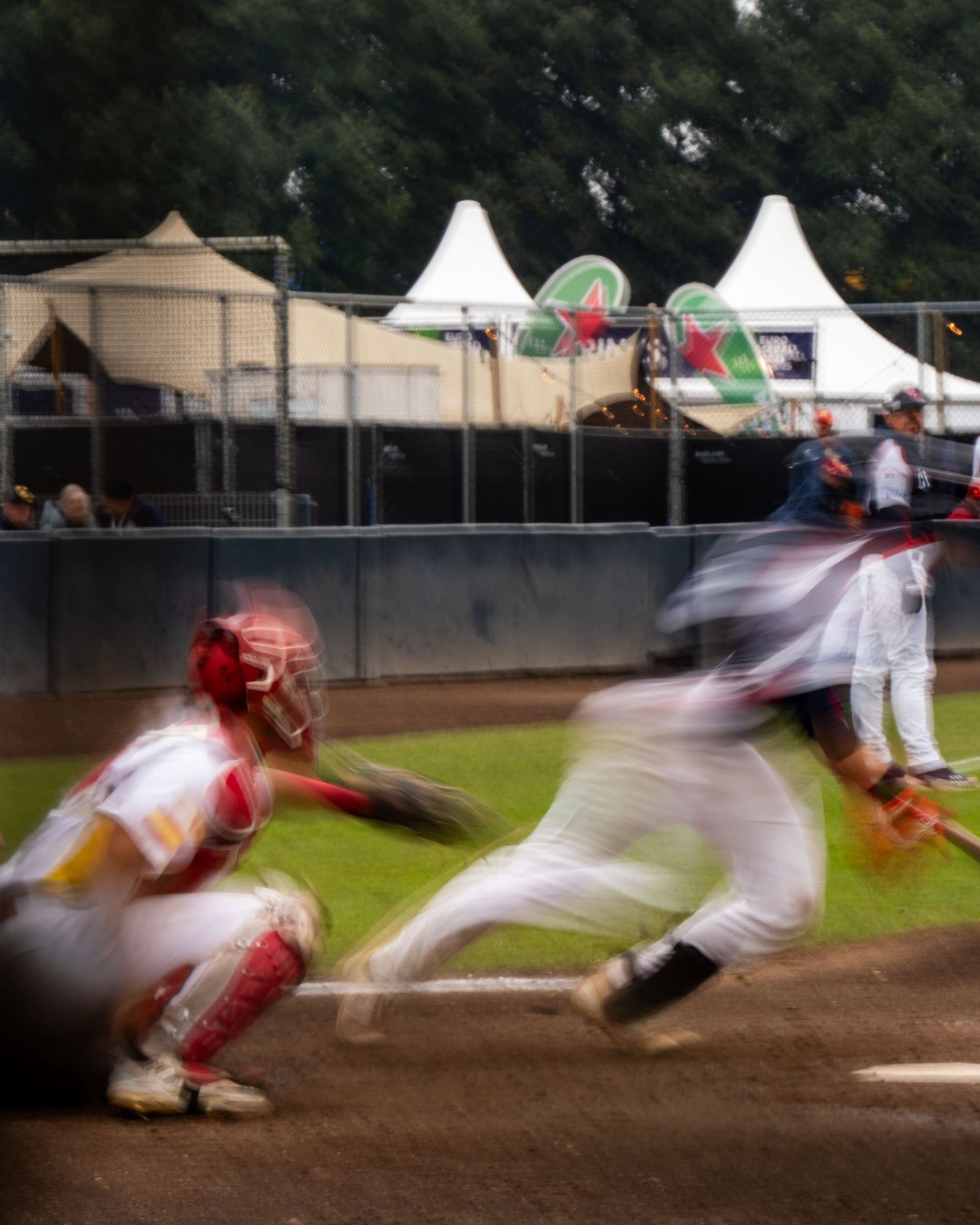 Baseball player slides into base during game with motion blur effect showing dynamic movement on field.