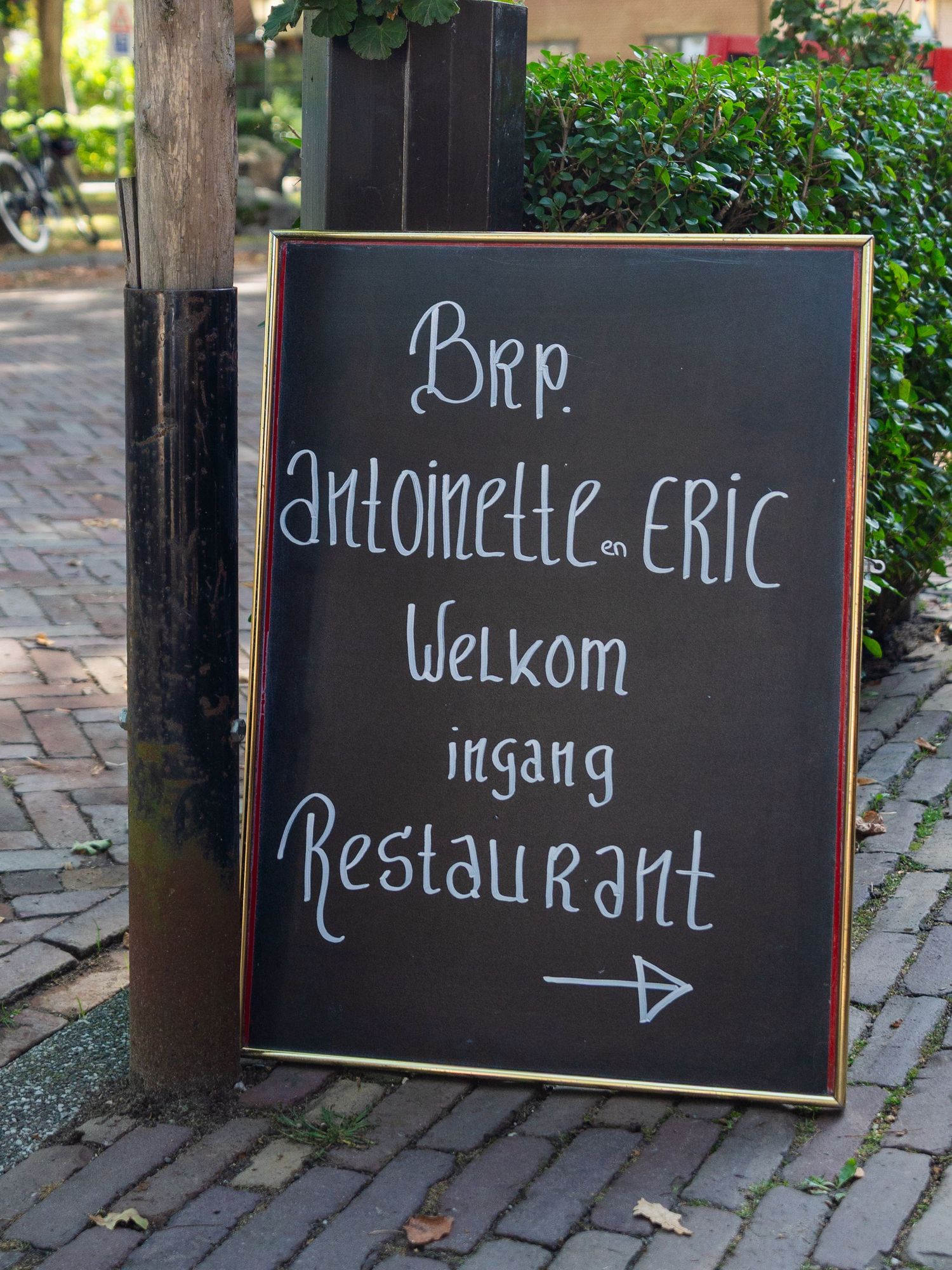 A series of black chalkboard signs with white text showing directional arrows and welcome messages for a restaurant entrance.