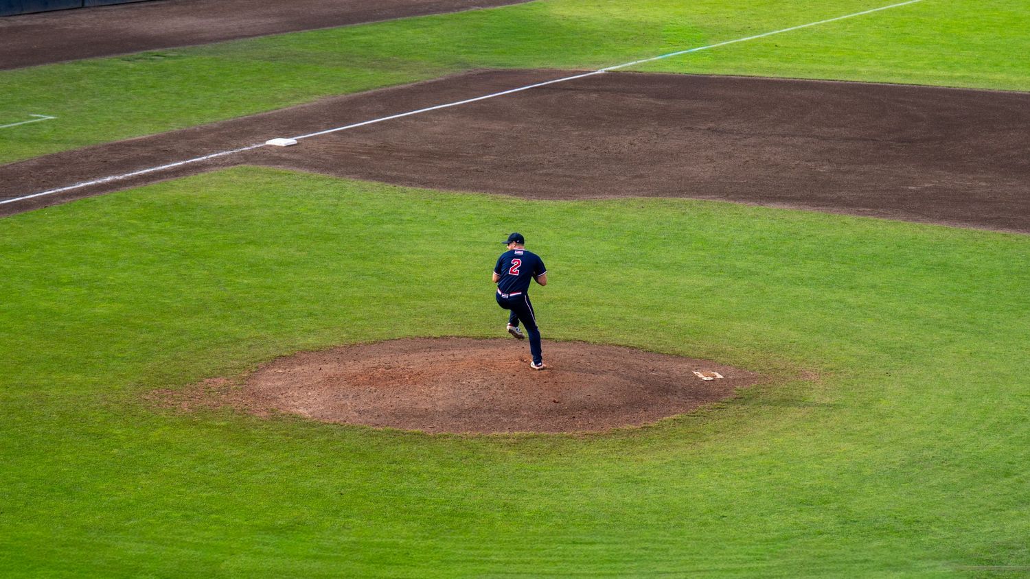 Baseball player on a green field makes a diving catch during a game.
