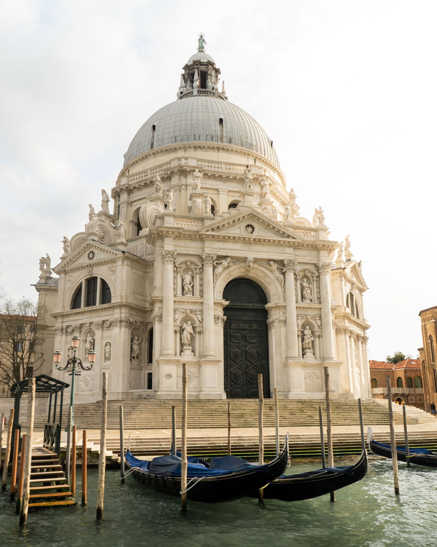 Gondolas moored on the Grand Canal in front of the ornate Baroque Santa Maria della Salute basilica in Venice, Italy.