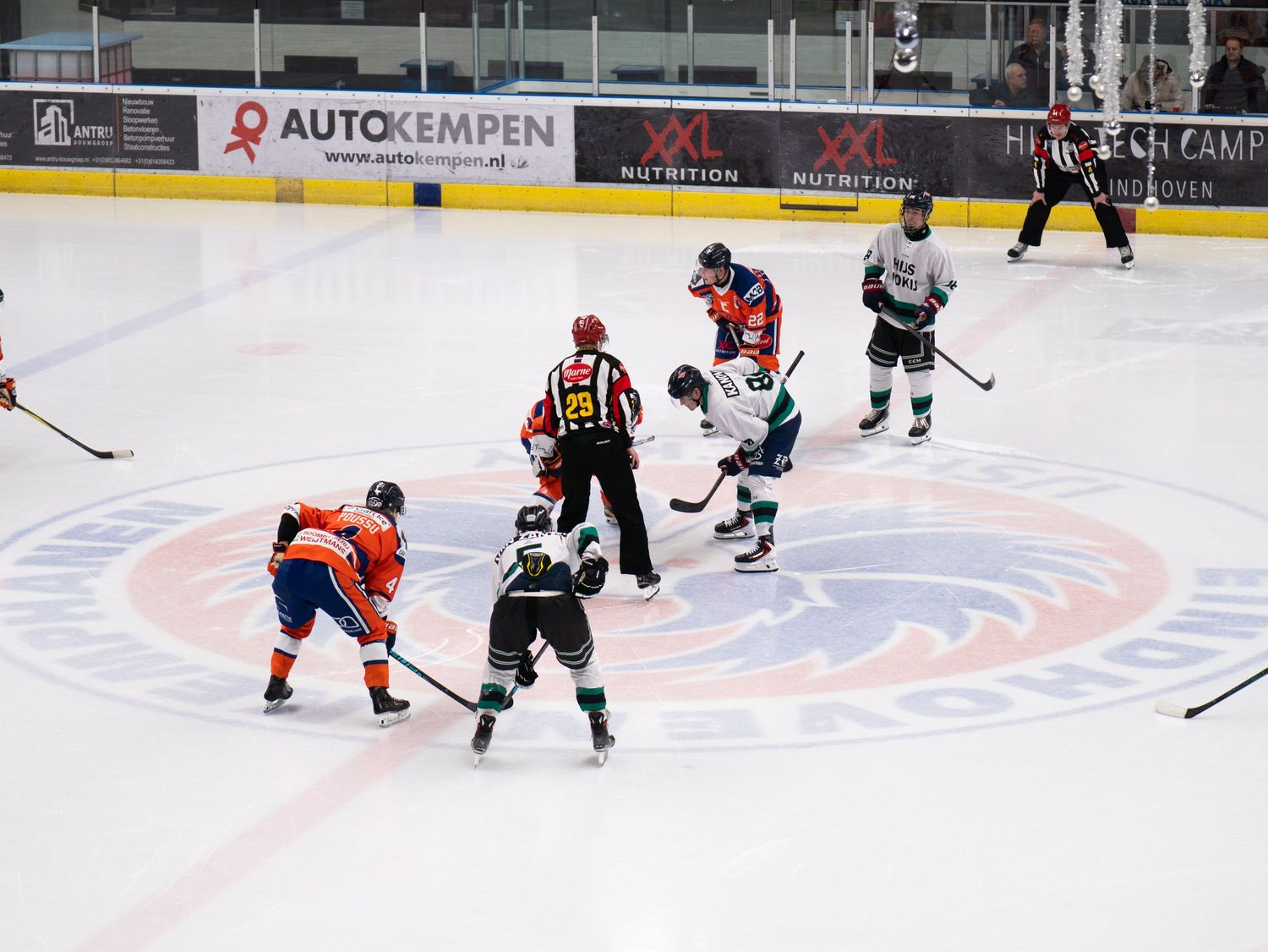 Hockey players compete during an ice hockey match with advertising boards visible in the background.