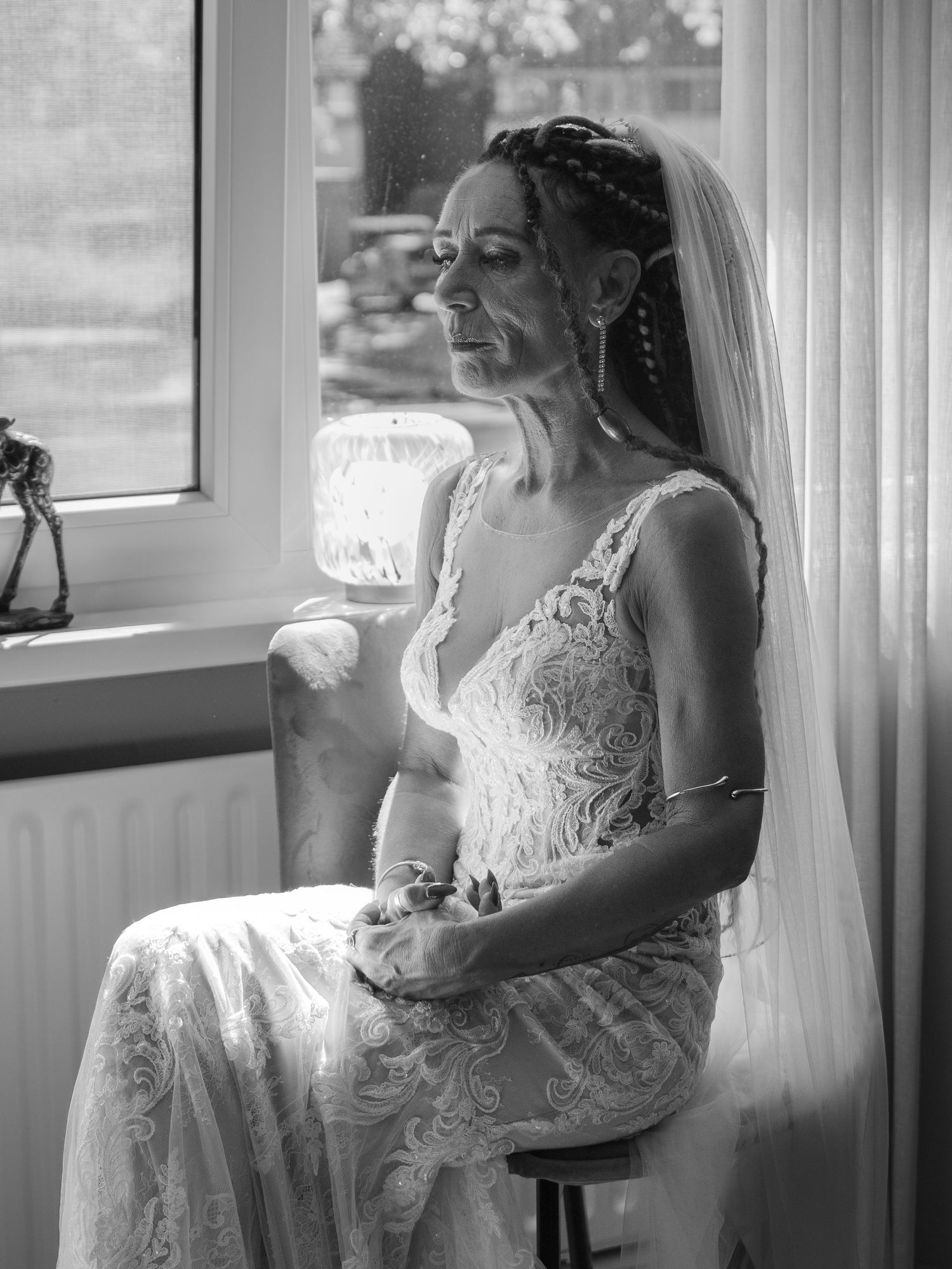 A sequence of black and white photos shows a bride in a lace wedding dress by a window in soft natural light.
