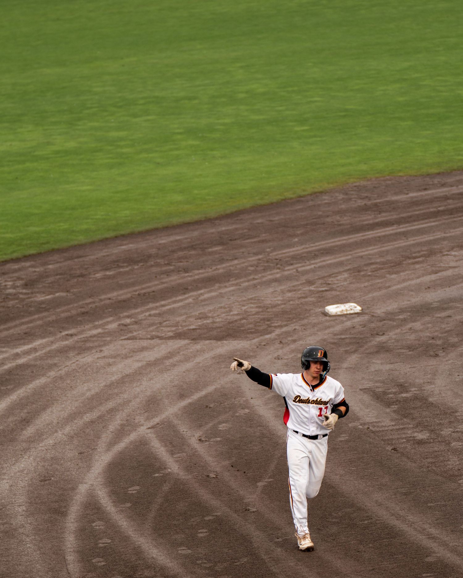 Baseball player demonstrates pitching motion sequence on brown dirt infield against green grass background.