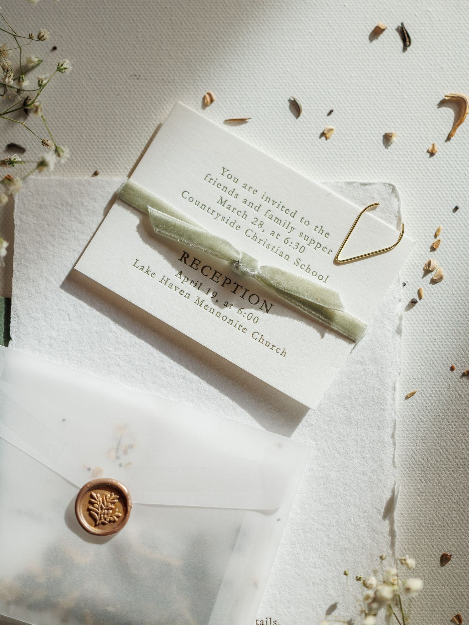White stationery items and wax seals arranged in an elegant flat lay composition with scattered dried petals.