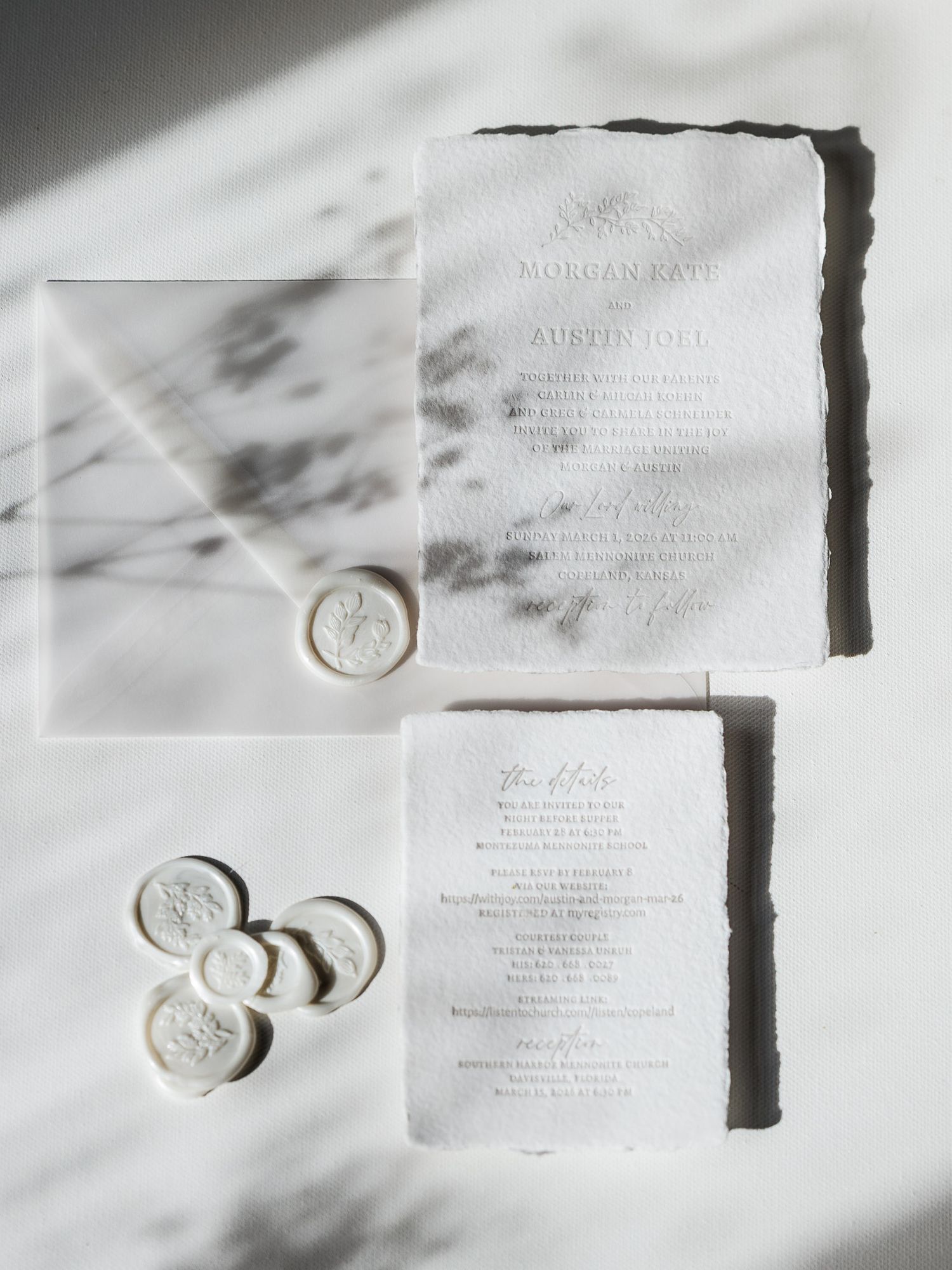 Elegant wedding invitation suite with wax seals and calligraphy on white textured paper in natural lighting.