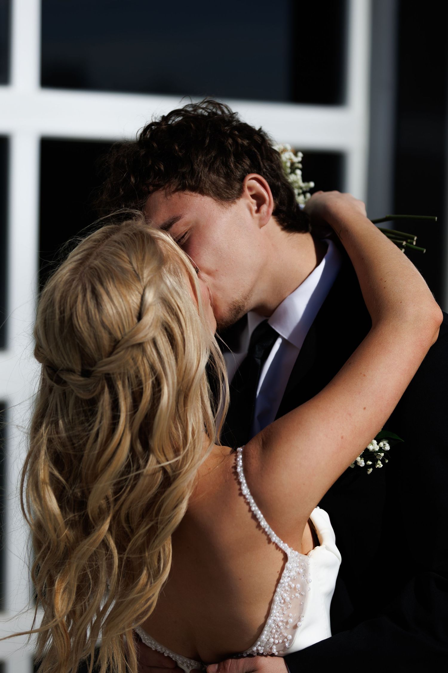 A bride and groom share a romantic kiss at their wedding ceremony, with the bride in a white lace dress.