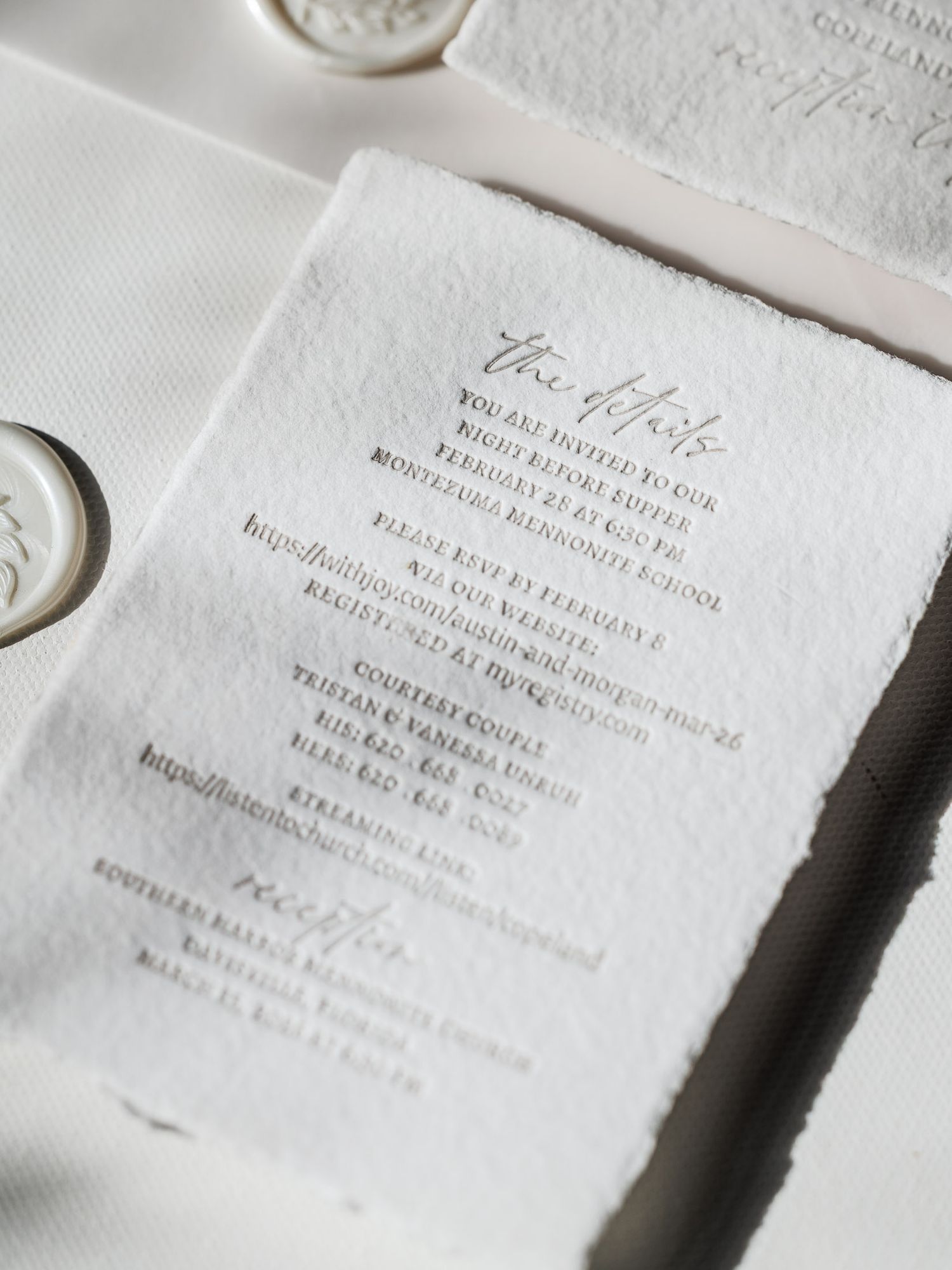Close-up view of elegant white wedding invitation cards with embossed text and delicate details.