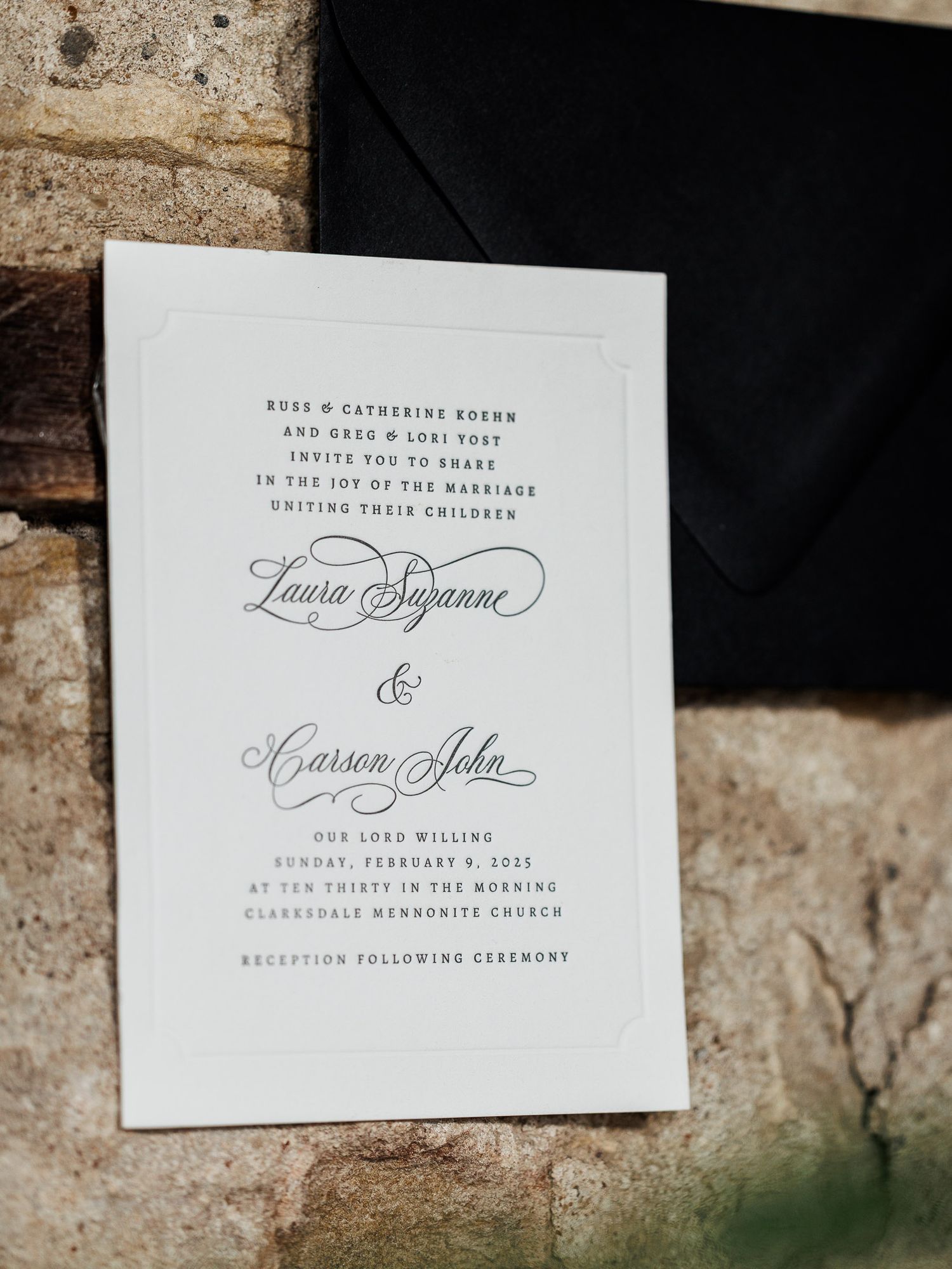 Elegant white letterpress wedding invitation with calligraphy script text displayed against a textured stone background.