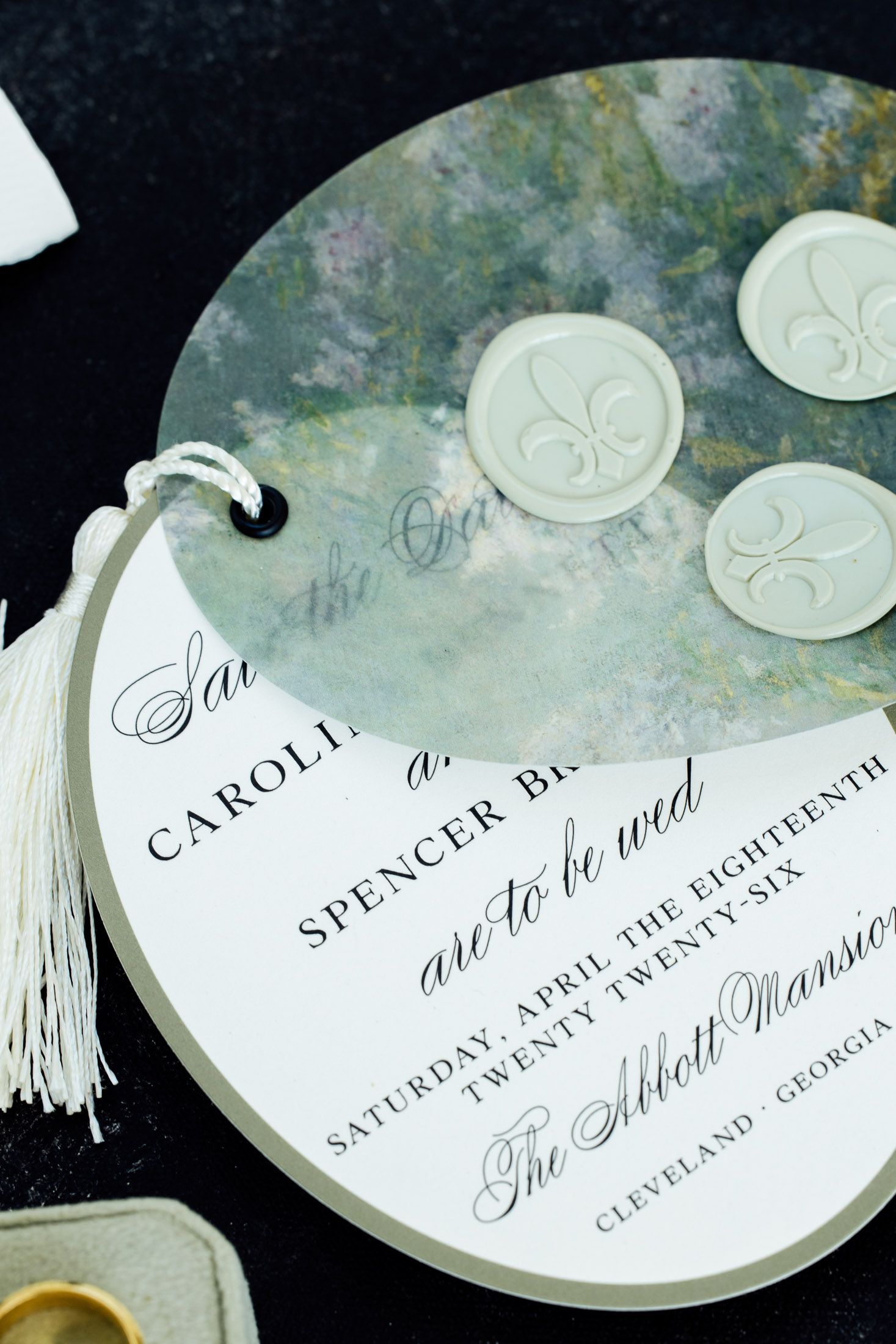 Elegant circular wedding save-the-date card with wax seals, tassel, and script text for Abbott Mansion, Cleveland, Georgia.