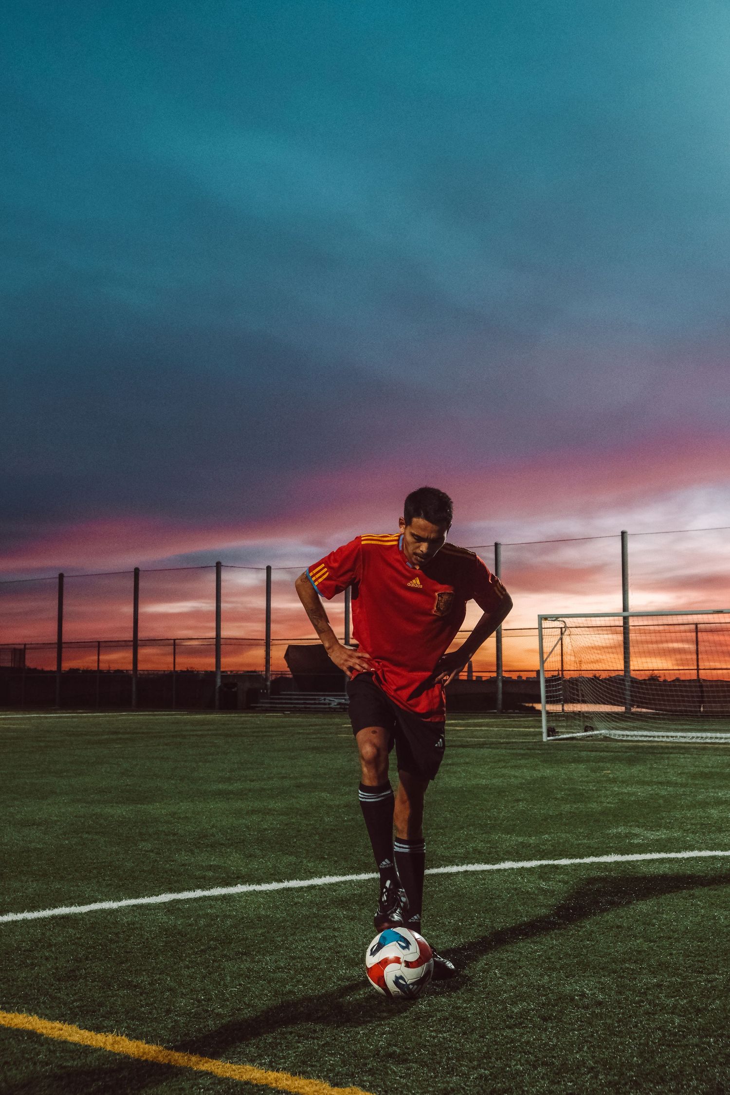 Creative portrait of a soccer player with a vibrant sunset sky in the background in Berkeley, CA.