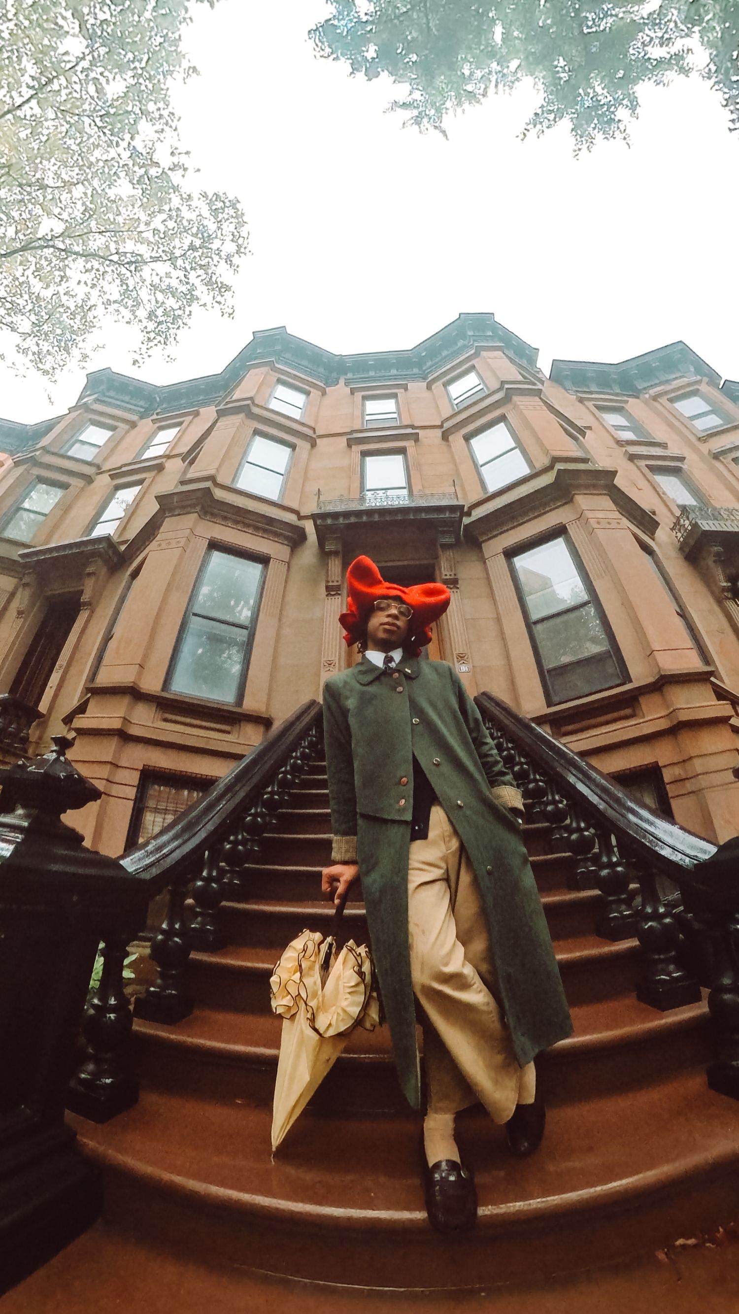 Artistic Brooklyn portrait of Ajai Kasim in front of brownstone buildings, highlighting fashion and creativity.