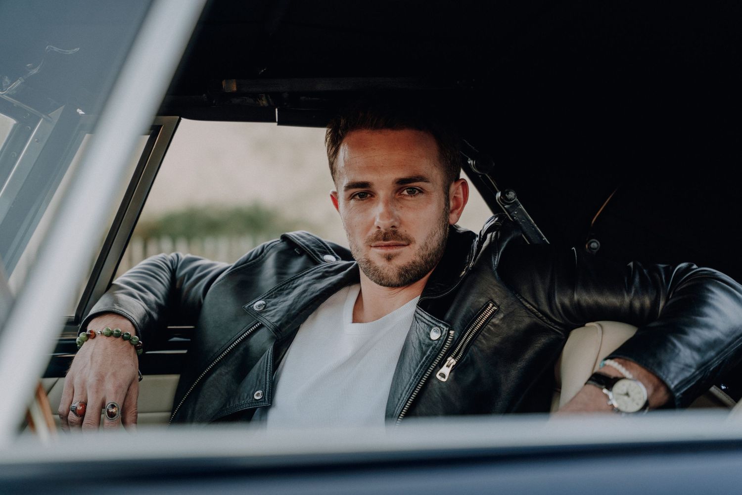 Moody automotive portrait through car window with dramatic lighting.