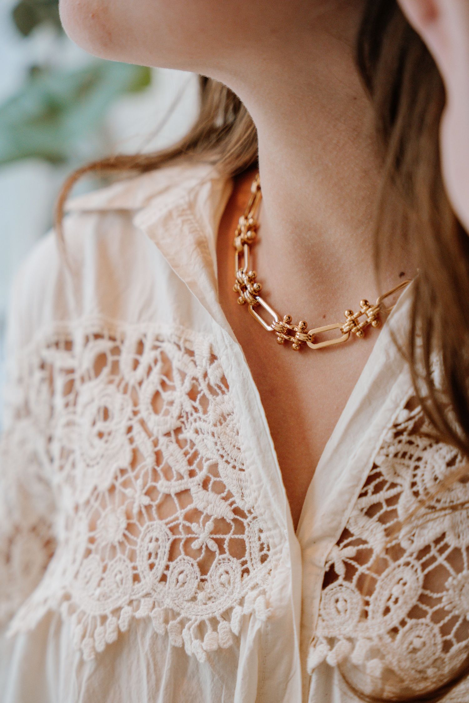 Close-up shots of delicate white lace collar details and a gold floral necklace against pale skin.