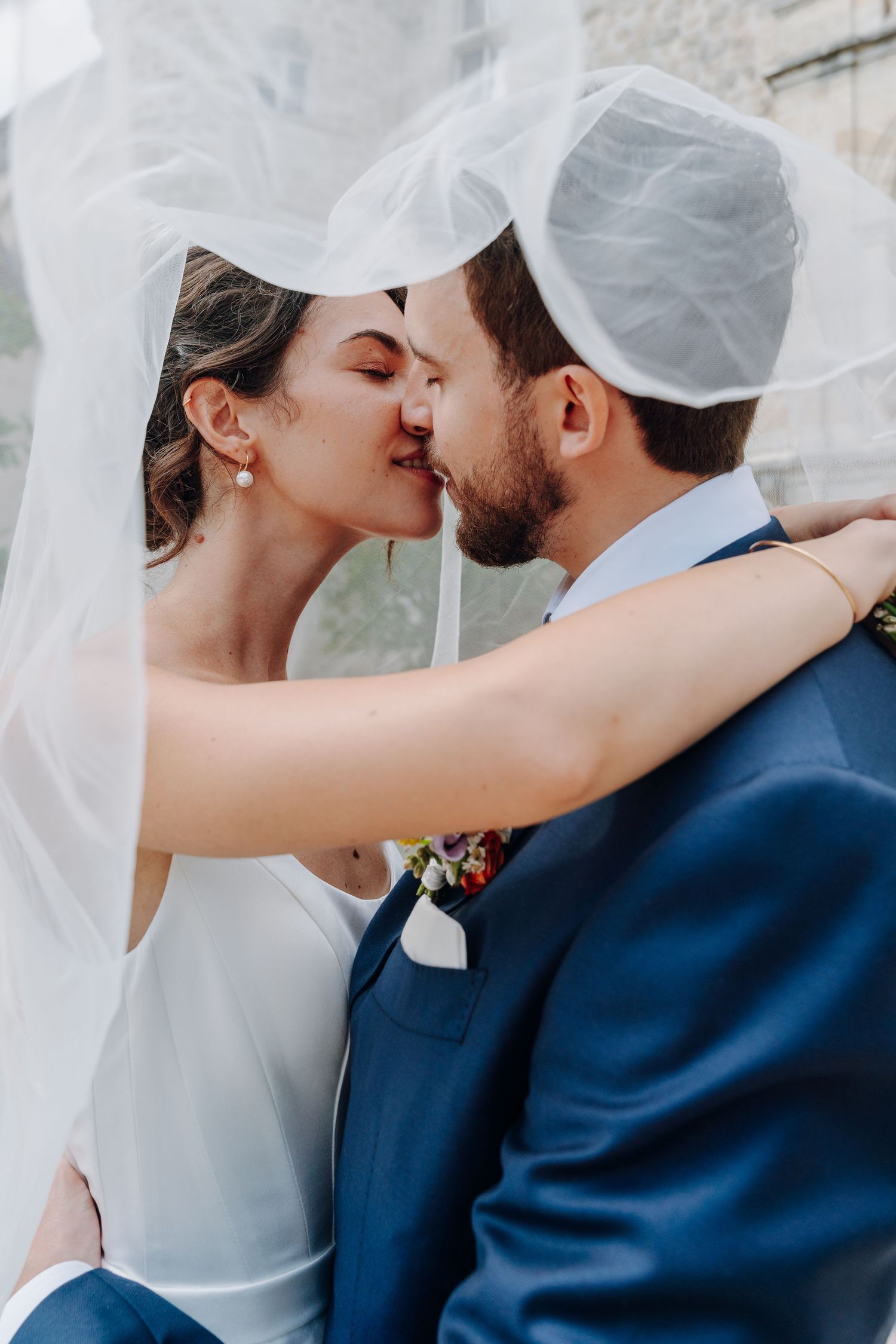 Intimate wedding portrait of couple sharing tender moment under flowing veil.