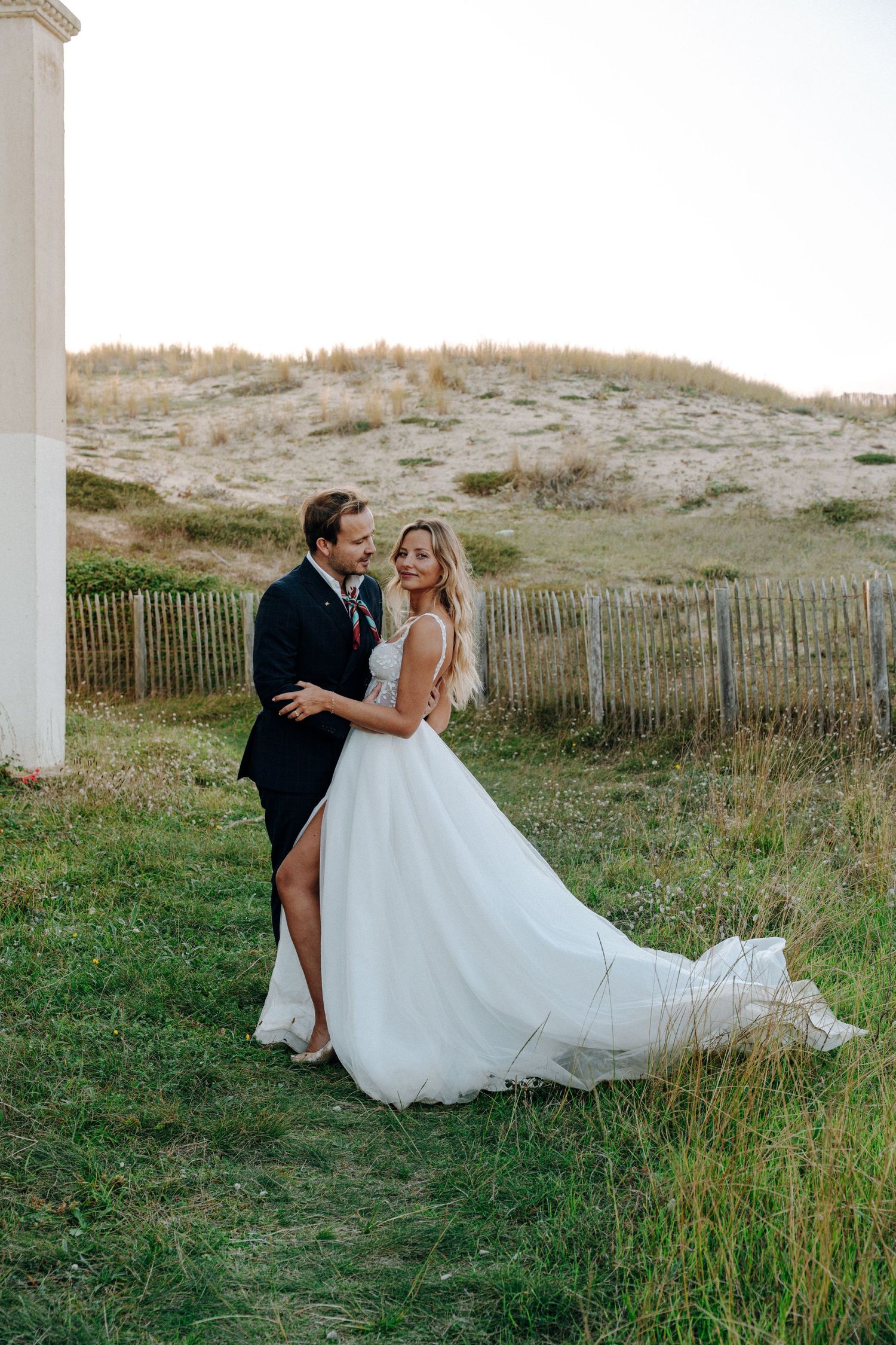 A romantic wedding photo session in a coastal setting with sand dunes.