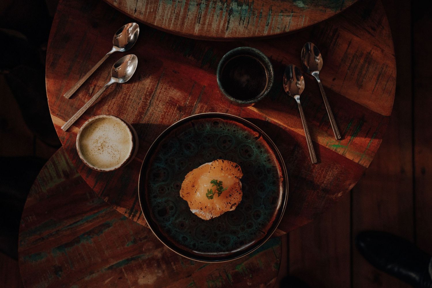 Dark and moody overhead shot of plates and drinks on wooden table.