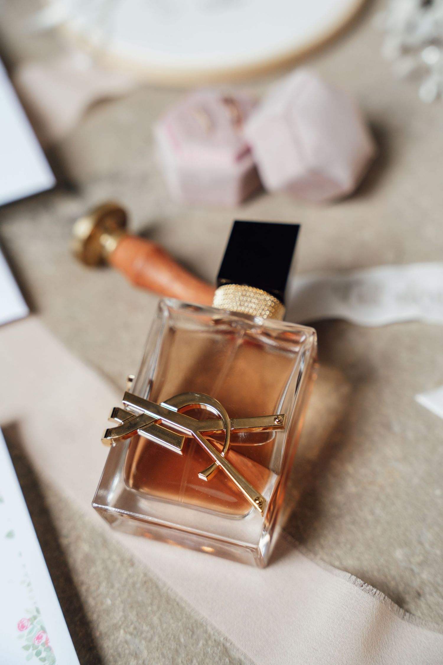 Elegant glass perfume bottles with gold accents arranged in a row on a soft beige surface.