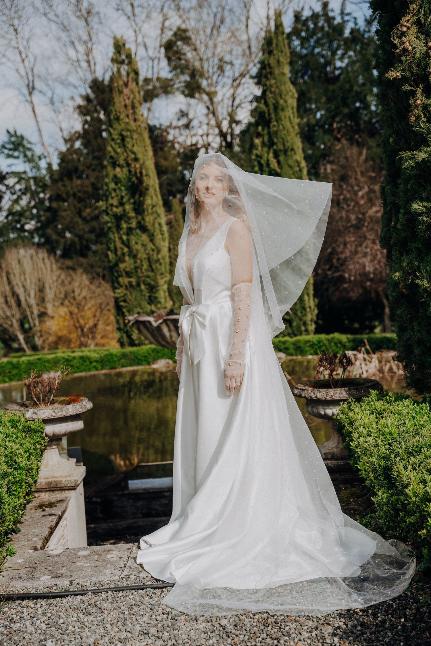 Ethereal bridal portraits in a garden setting with flowing white dress and veil.