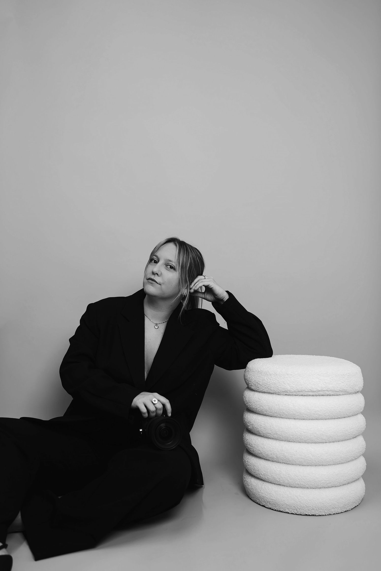 Artistic black and white portrait with white circular cushions as props.
