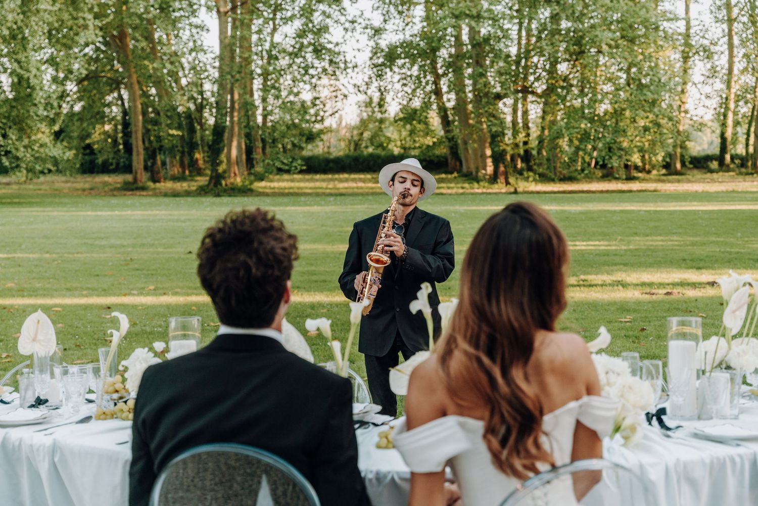 Outdoor wedding reception with musician performing for seated guests.
