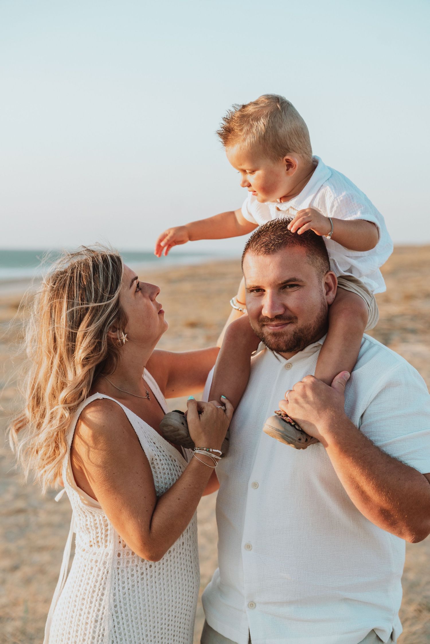 Family sharing intimate moments and laughter on beach at sunset.