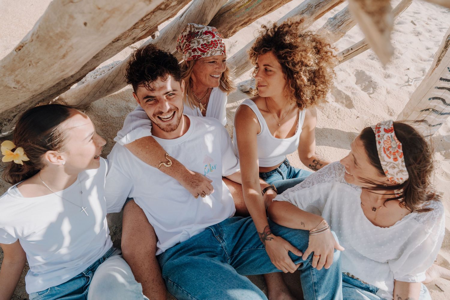 Happy group laughing and embracing while sitting together on beach.