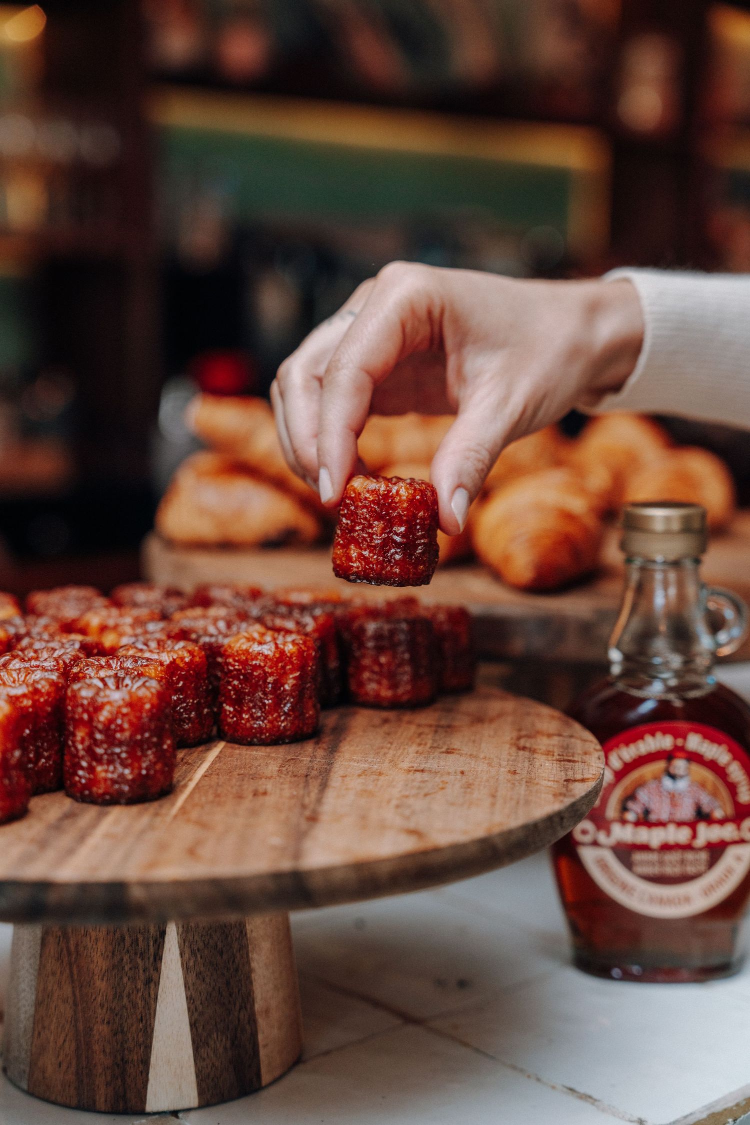 Close-up of sliced meat being arranged on wooden serving board with sauce bottle.