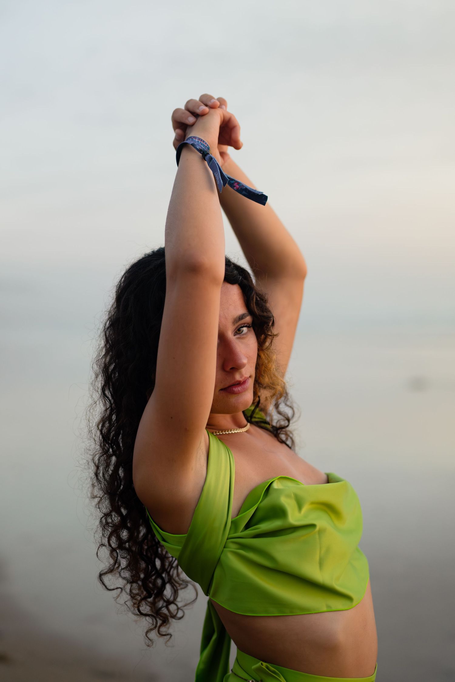 A series of four photos showing a person in a bright green top stretching their arms upward against a cloudy sky.