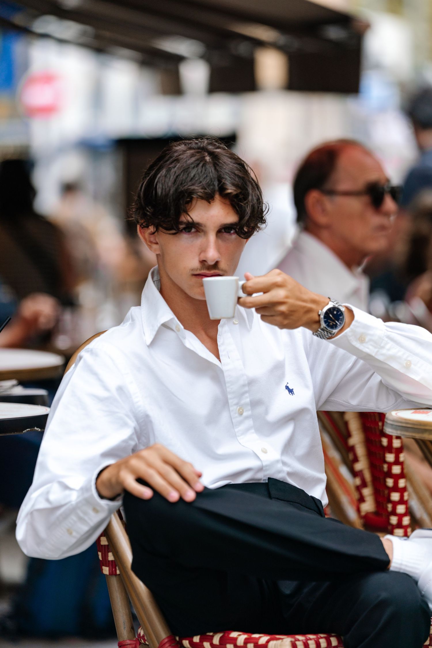 Young man in white shirt relaxing at outdoor cafe terrace.