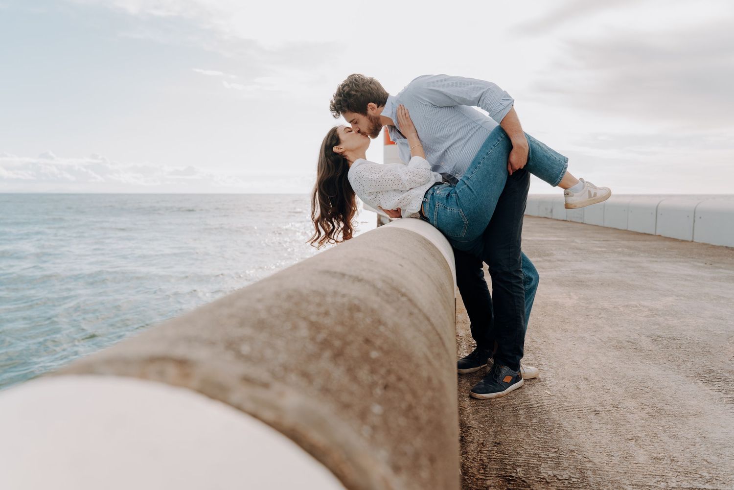 Romantic couple embracing on a scenic beach with waves crashing in the background.