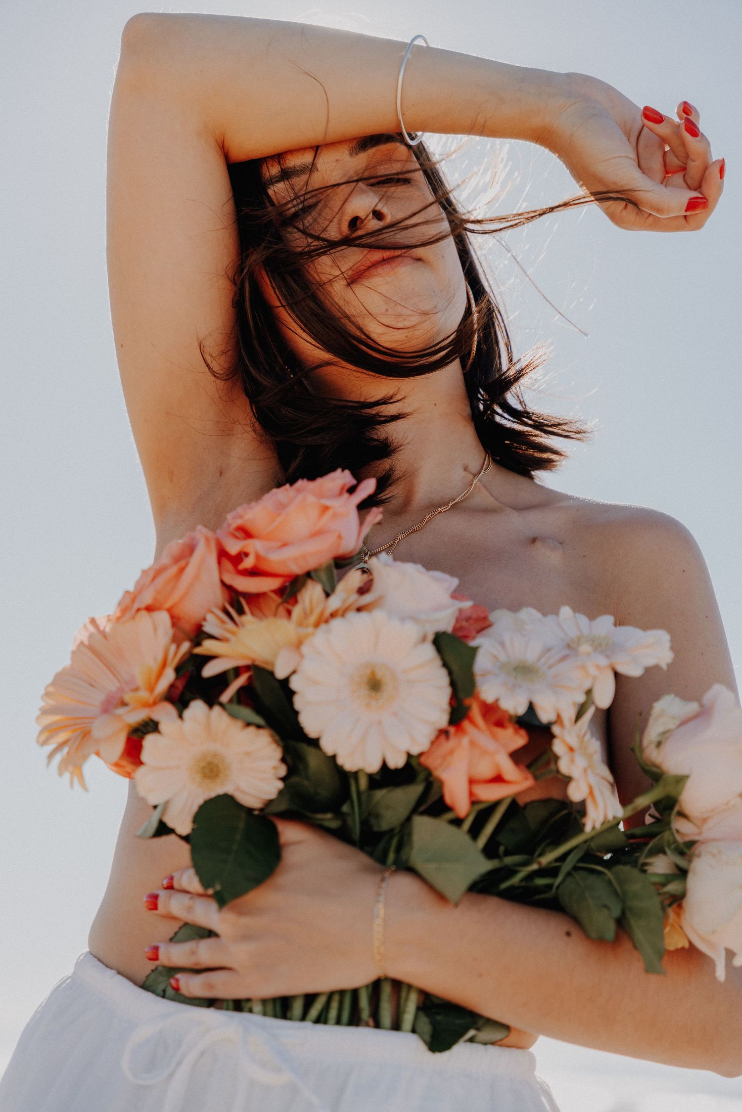 Artistic photo series showing person with dark hair holding white and peach colored flowers against light background.