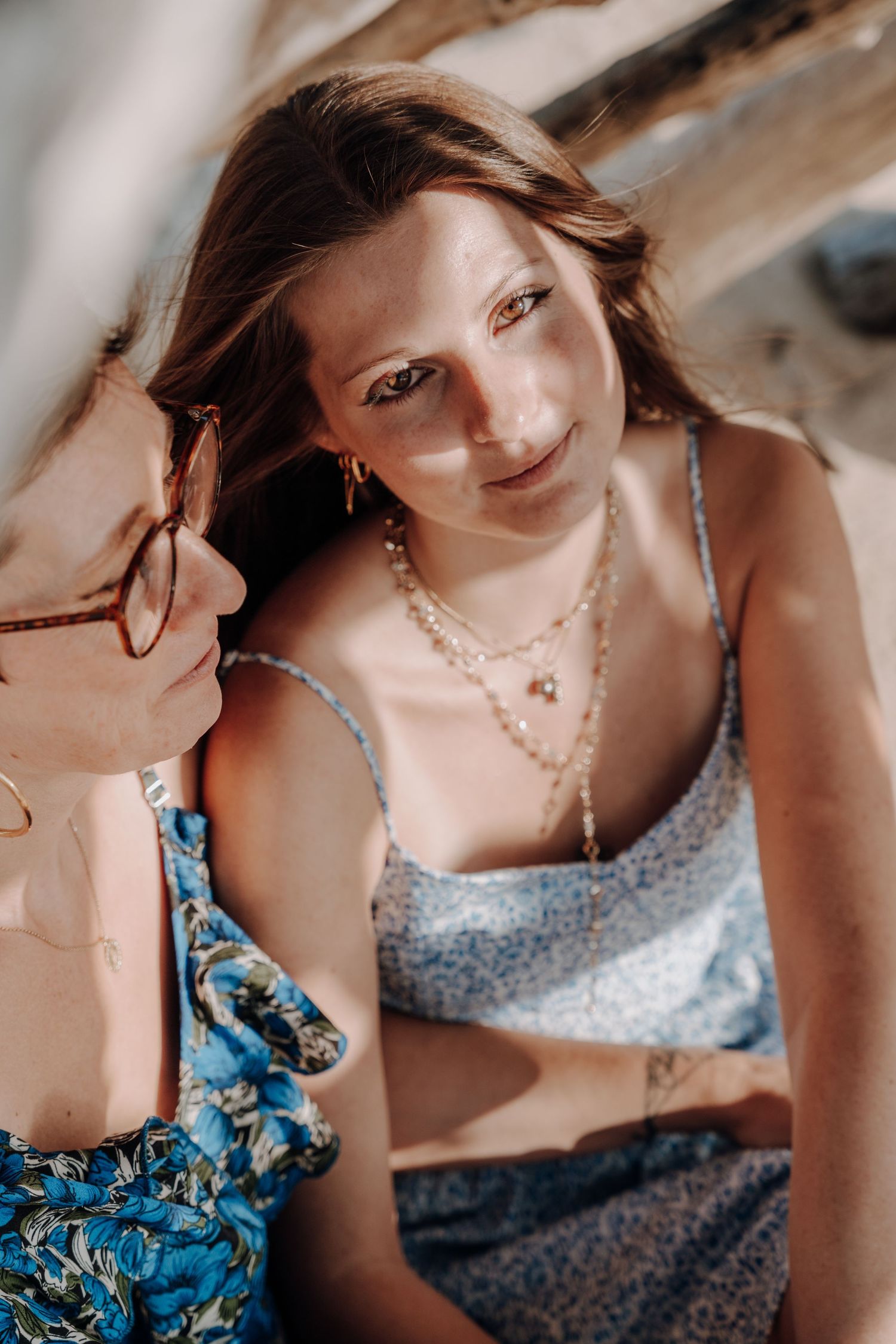 Close up portrait of person in floral dress with delicate necklace on beach.