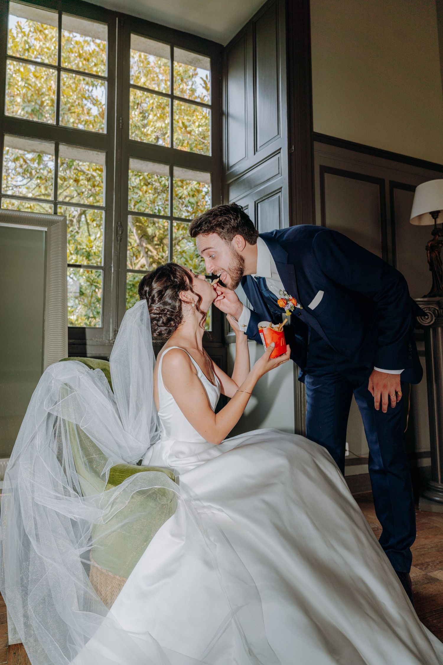 A romantic wedding moment captured by a window with natural light streaming in.