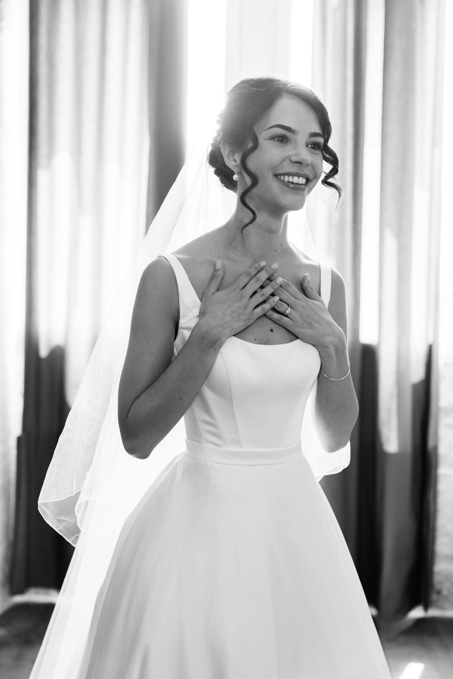 A bride in a white wedding dress laughs joyfully in a sequence of candid moments captured in black and white.