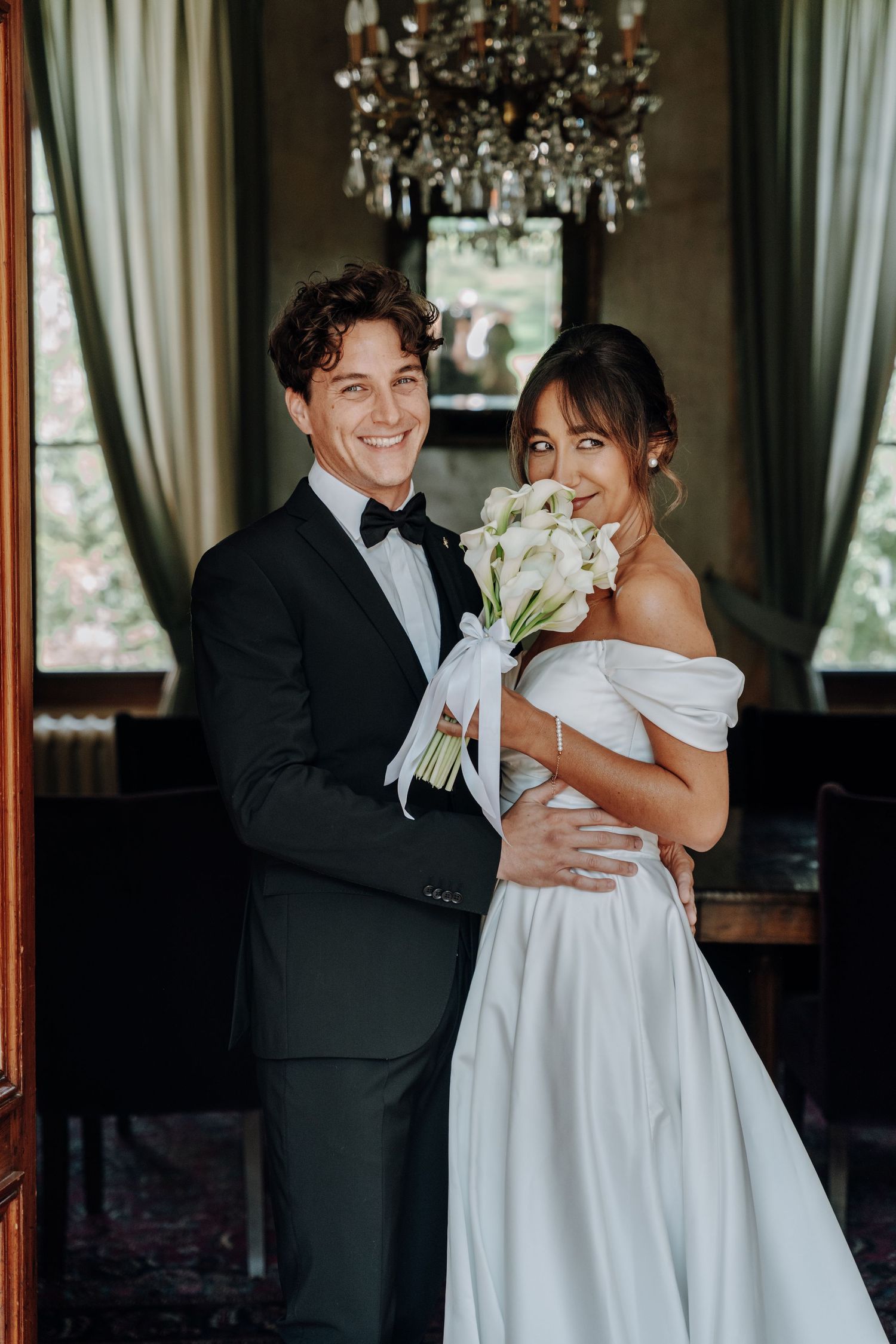 Elegant wedding portrait under crystal chandelier in formal setting.