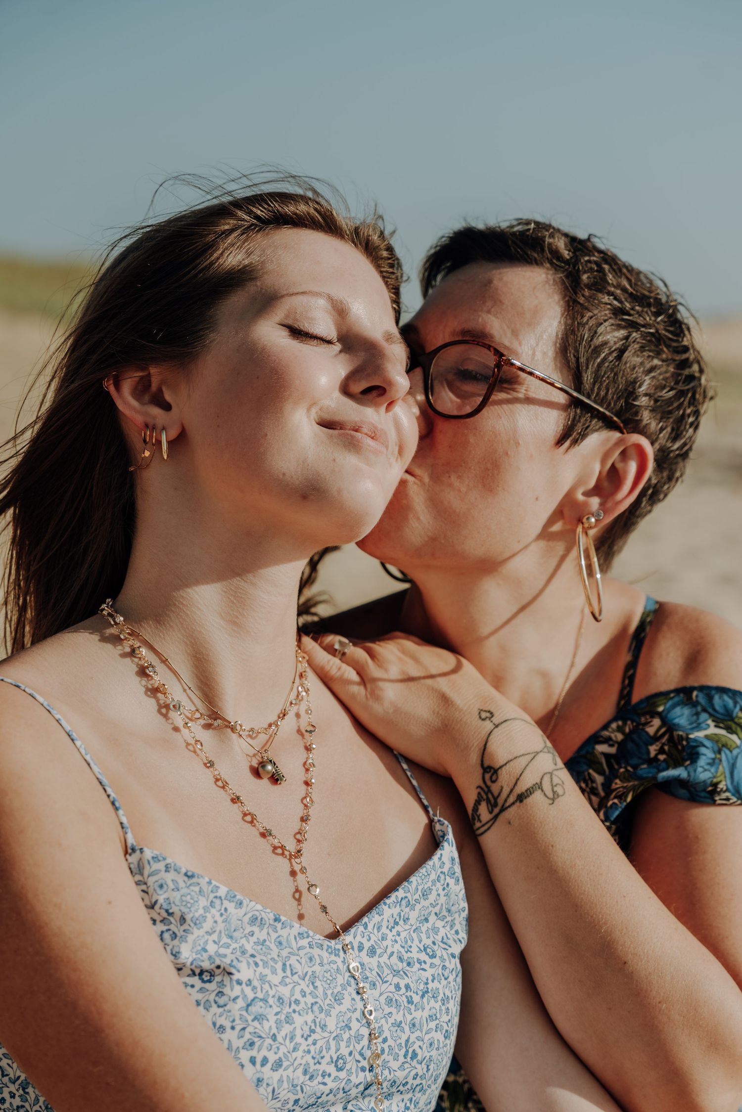 Intimate moment between two people in summer dresses on beach.