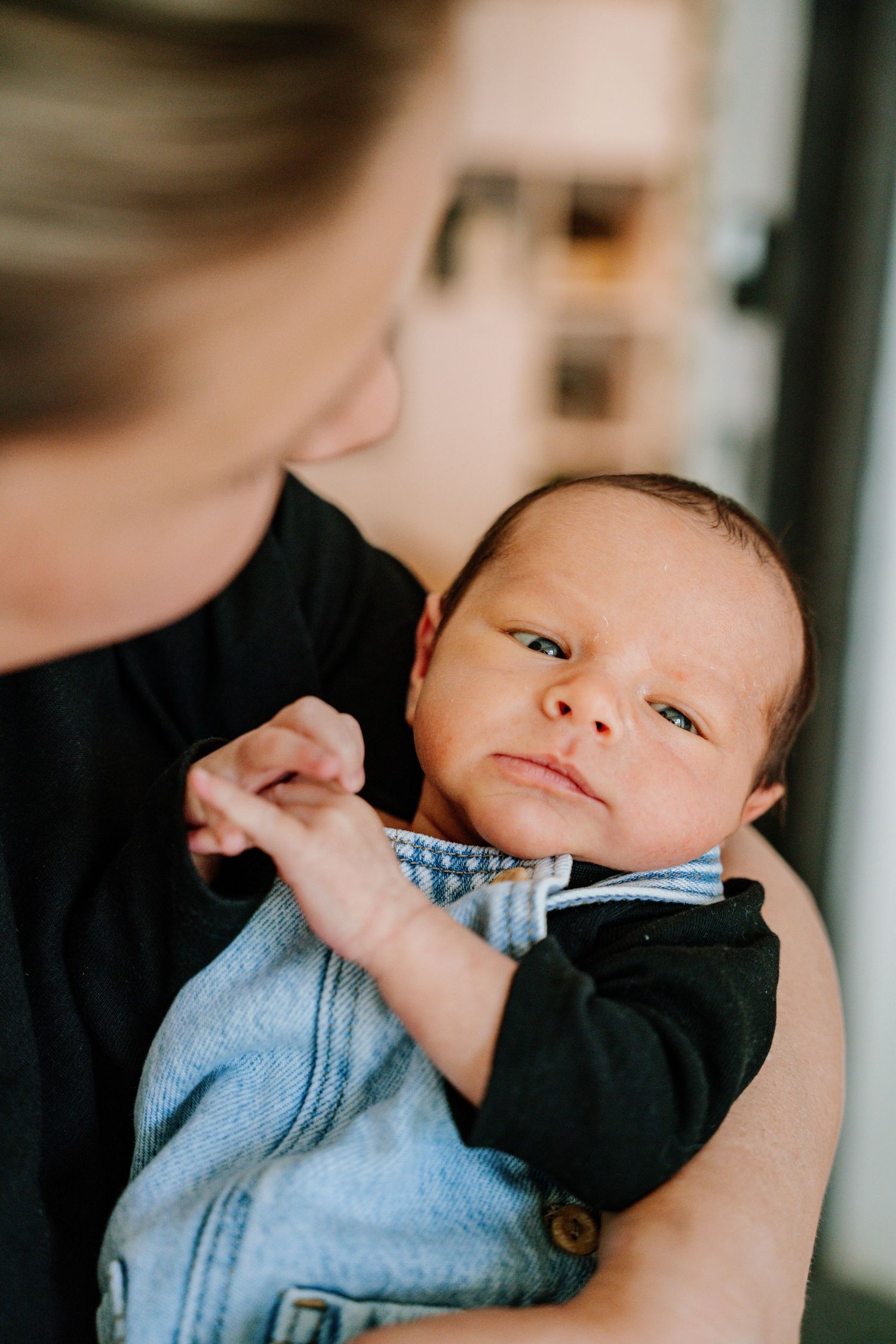 A baby in a blue and black outfit is held close while sleeping peacefully.
