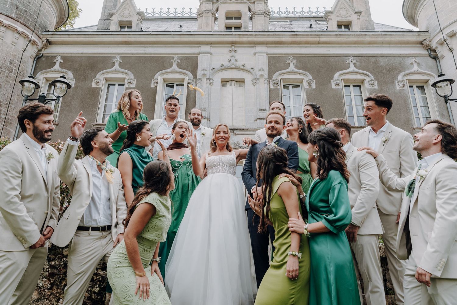 Wedding party celebrates with champagne outside ornate historic building.