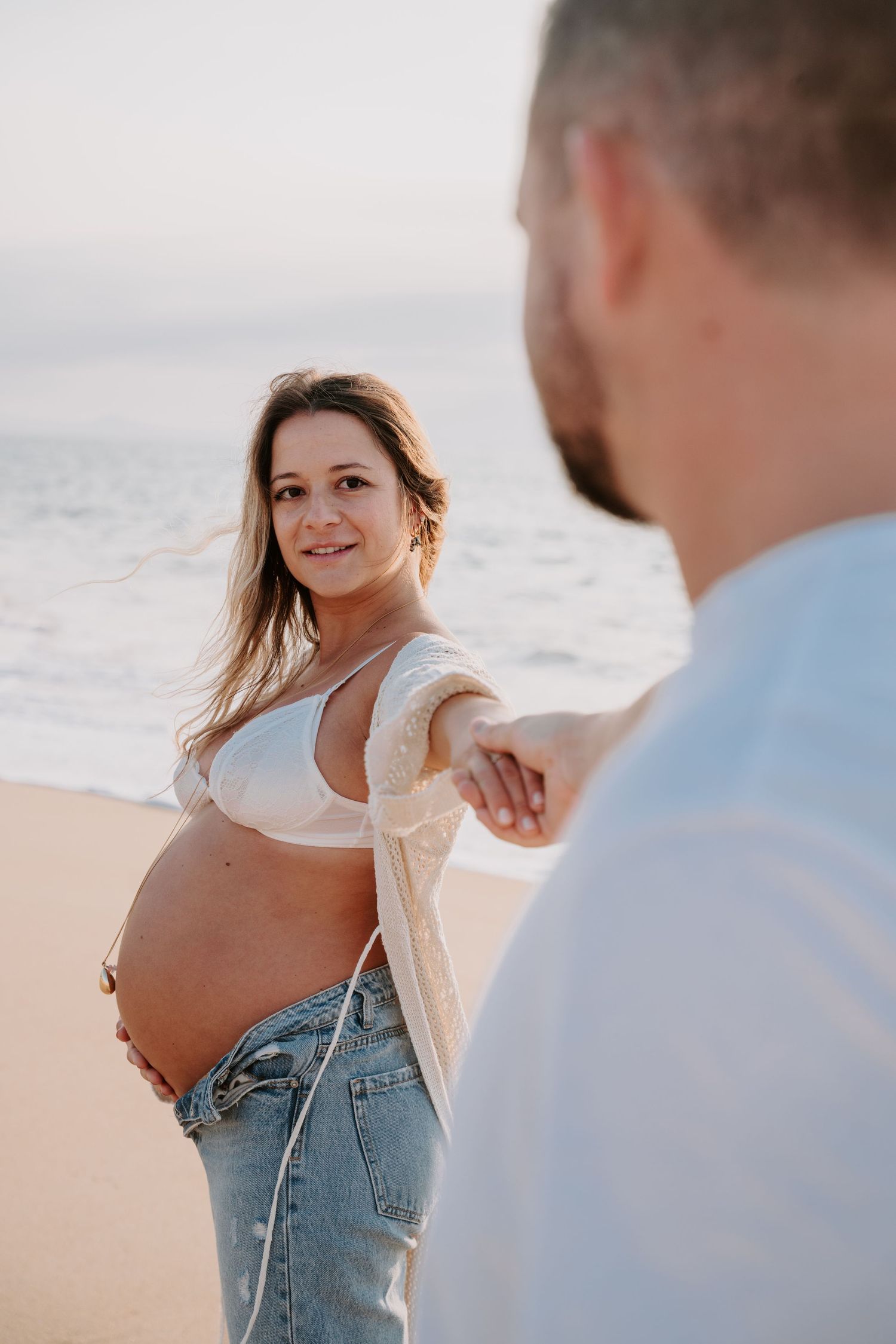 Candid beach photoshoot with soft natural lighting and ocean backdrop.