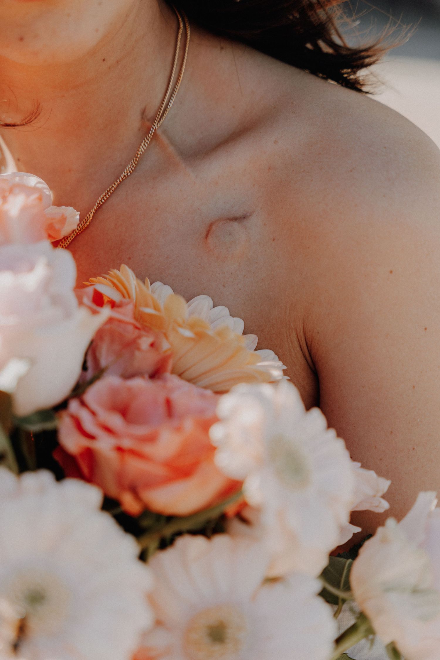 Soft peach and white roses frame a delicate neckline and bare shoulder in a dreamy, romantic composition.