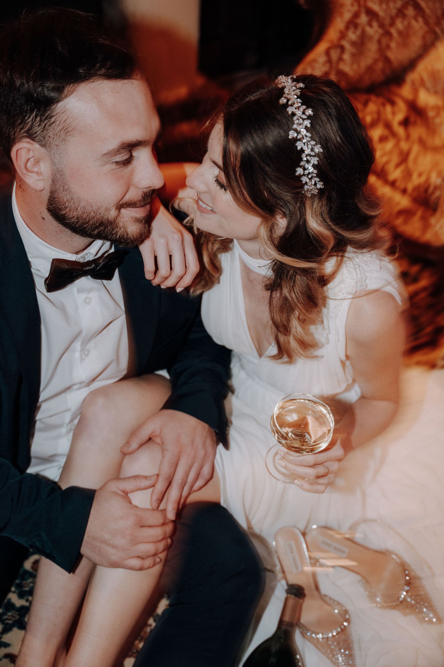 A romantic wedding couple shares an intimate moment while holding cocktails.