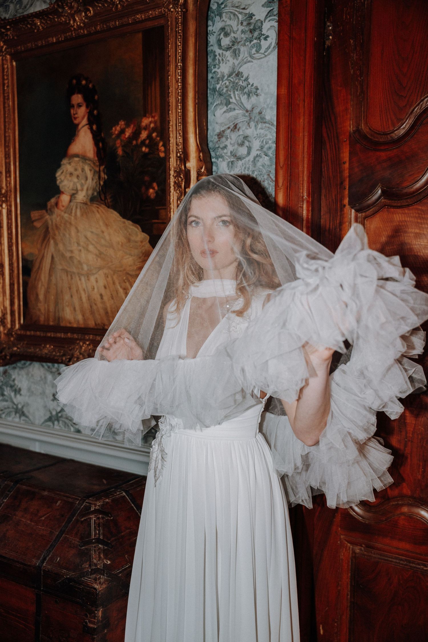 Dramatic bridal portraits in a vintage room with ornate wallpaper and flowing white dress.