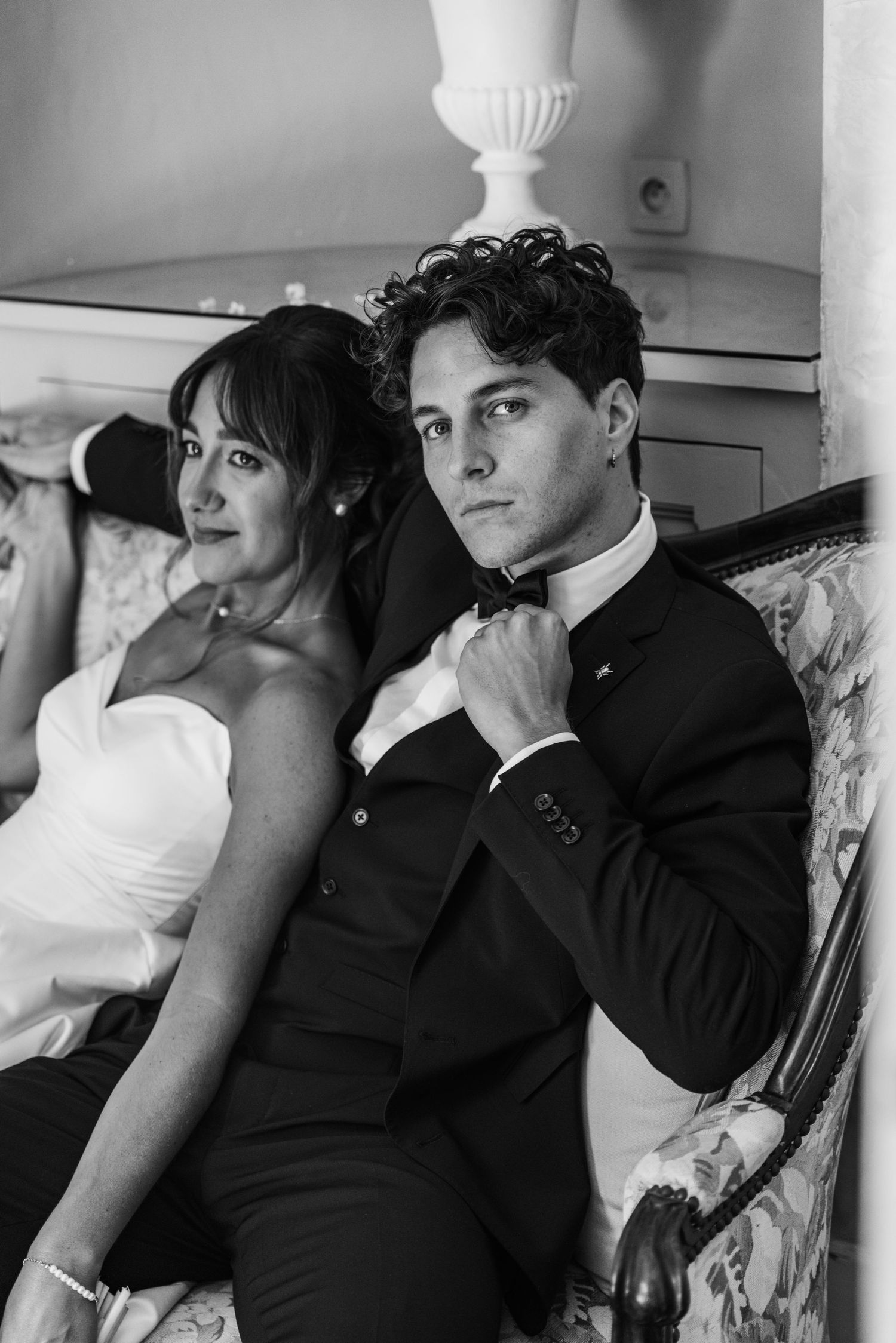 Black and white portrait of wedding party relaxing on vintage furniture.