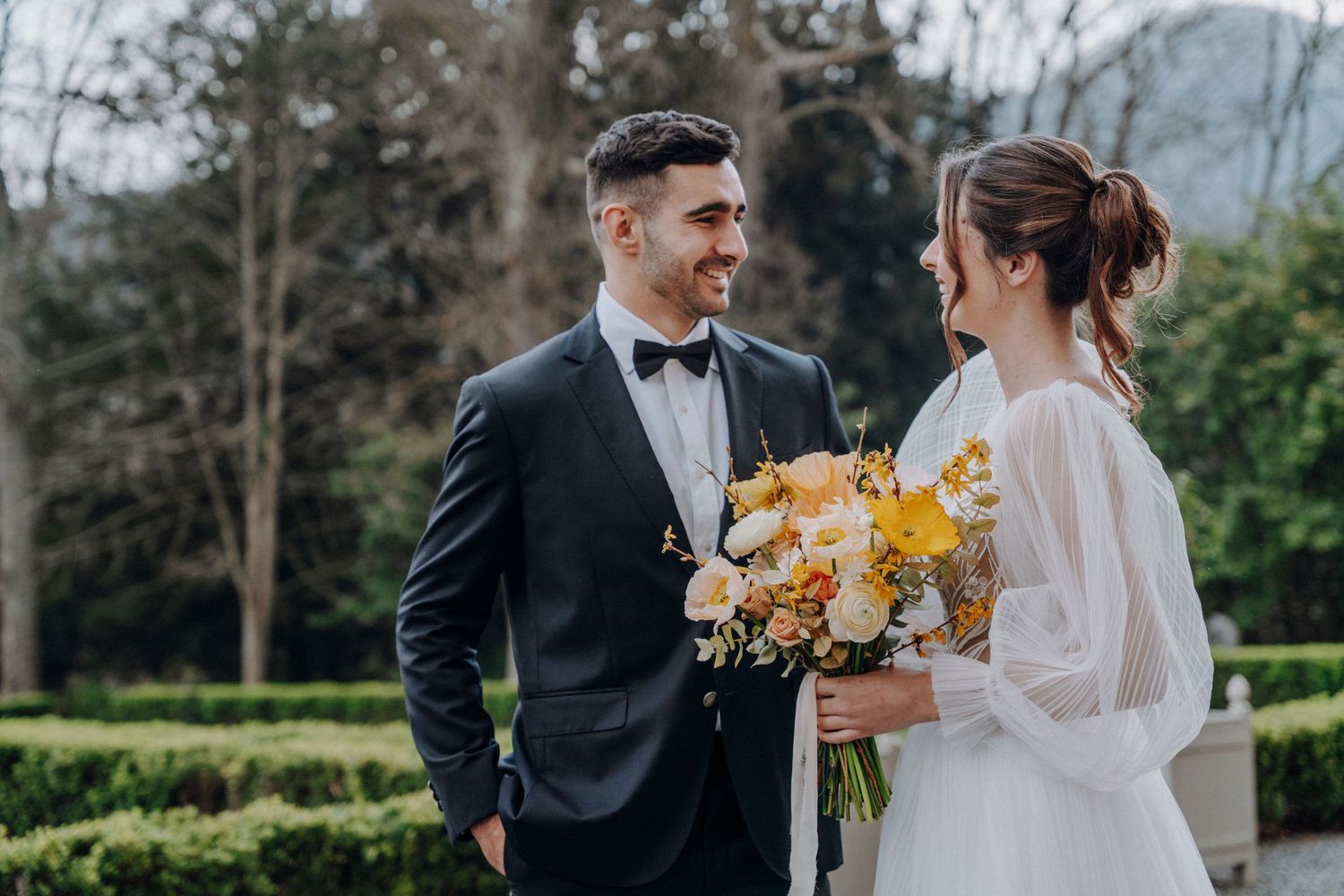 A romantic wedding photoshoot in an outdoor garden setting with mountains in the background.