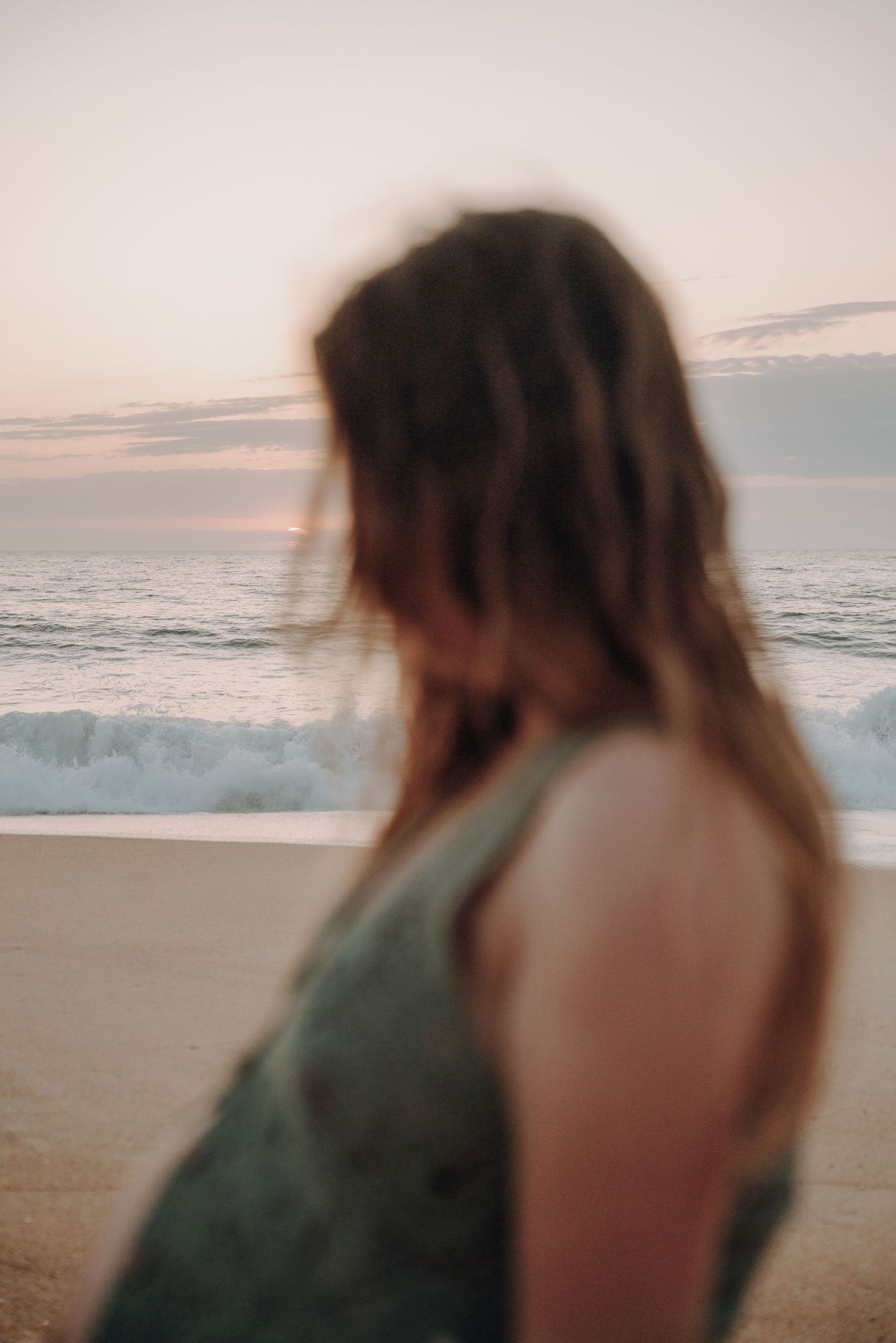 Artistic beach maternity photos with ocean waves and sunset in background.