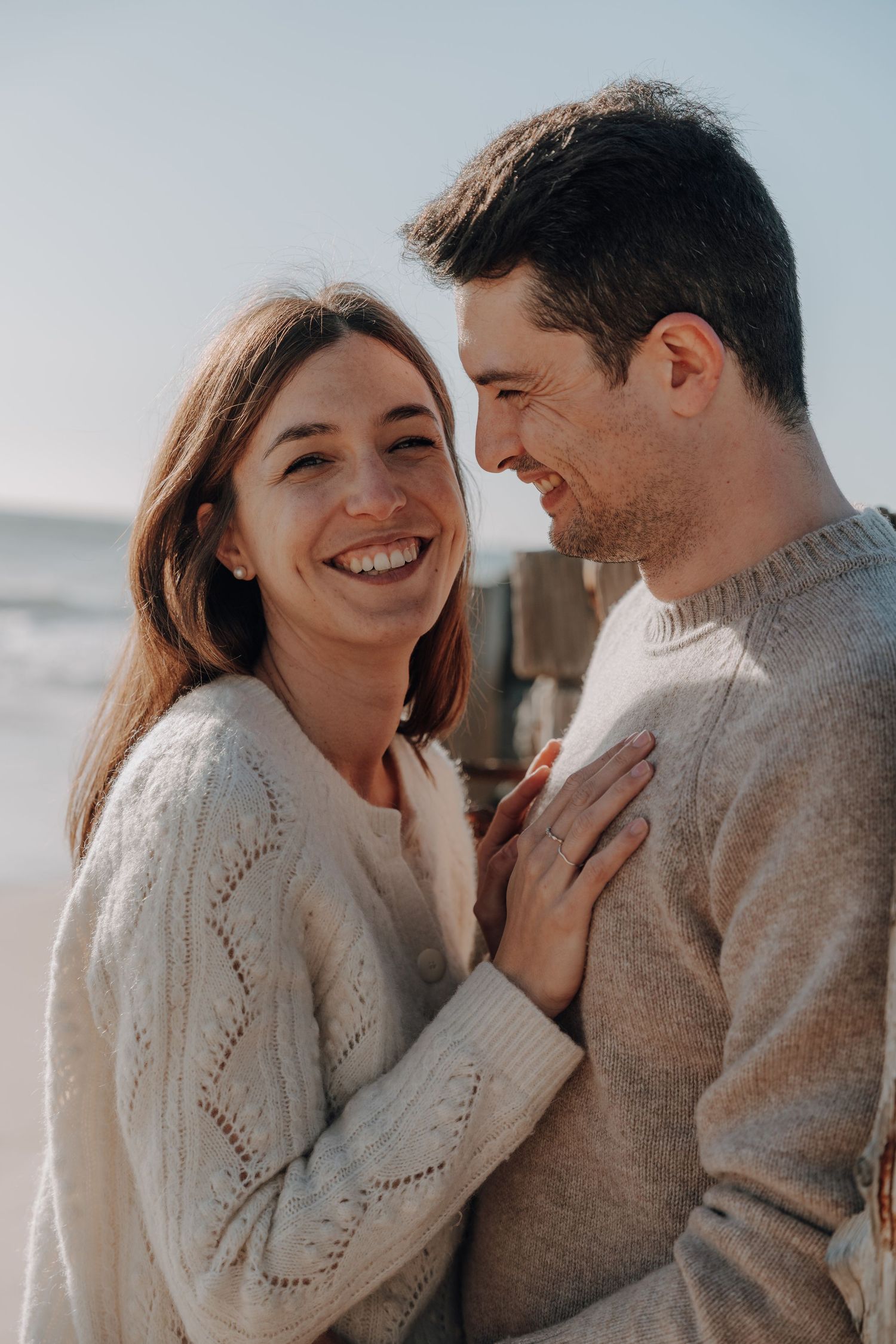 Cozy winter maternity session with couple in matching sweaters sharing loving moments.