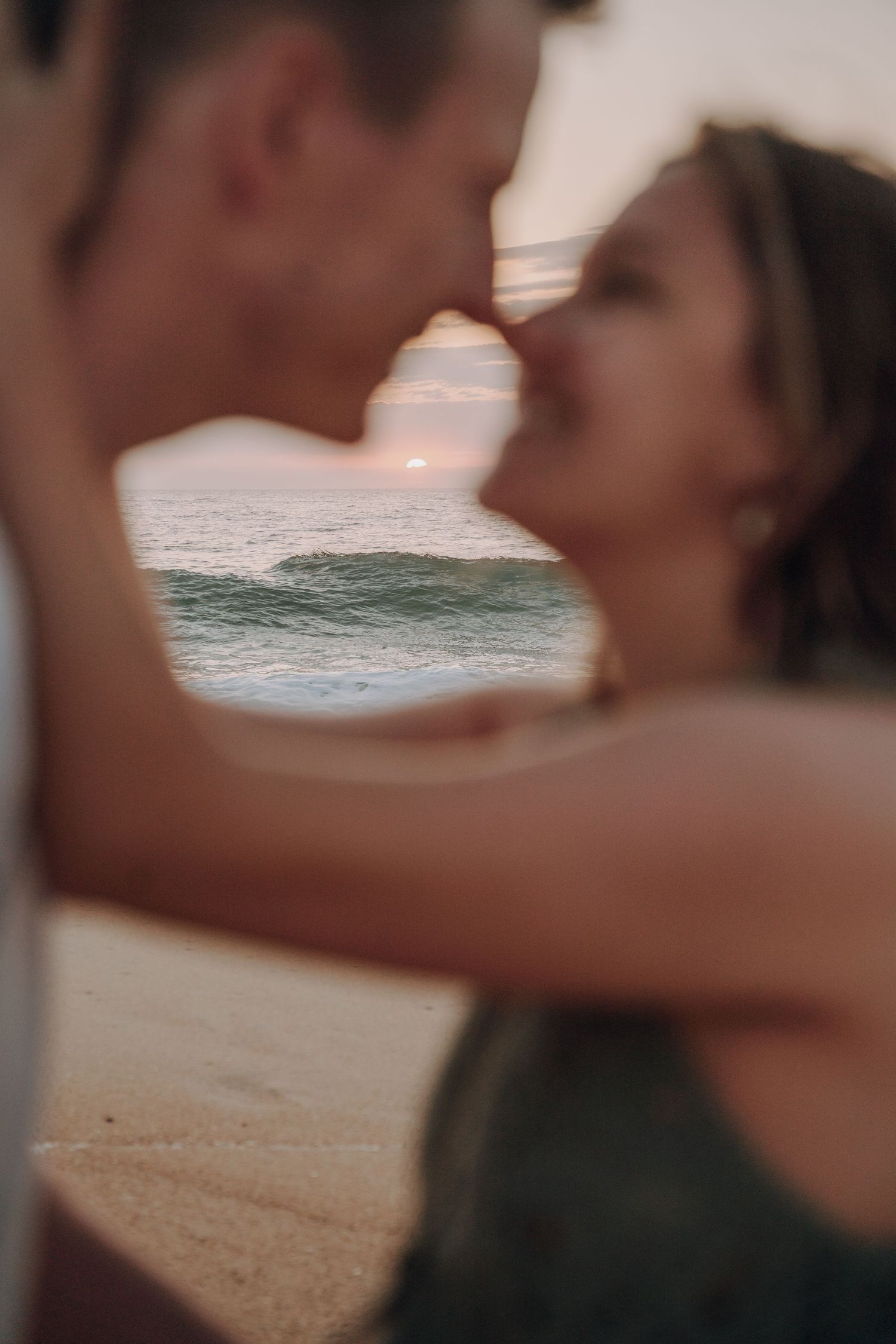 Silhouetted beach maternity photos with ocean waves in background at sunset.