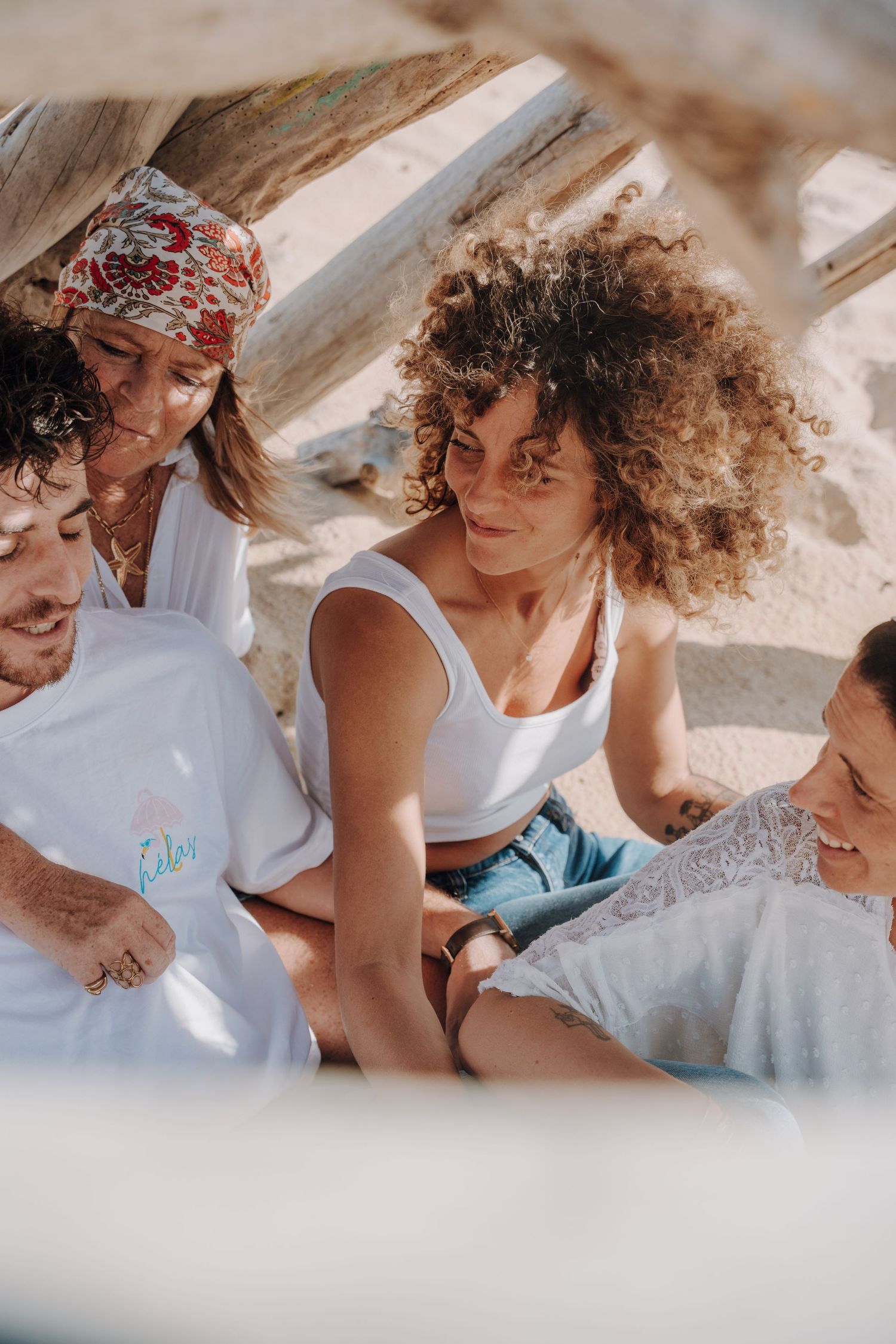 Friends sharing intimate conversations and laughter during beach photoshoot.