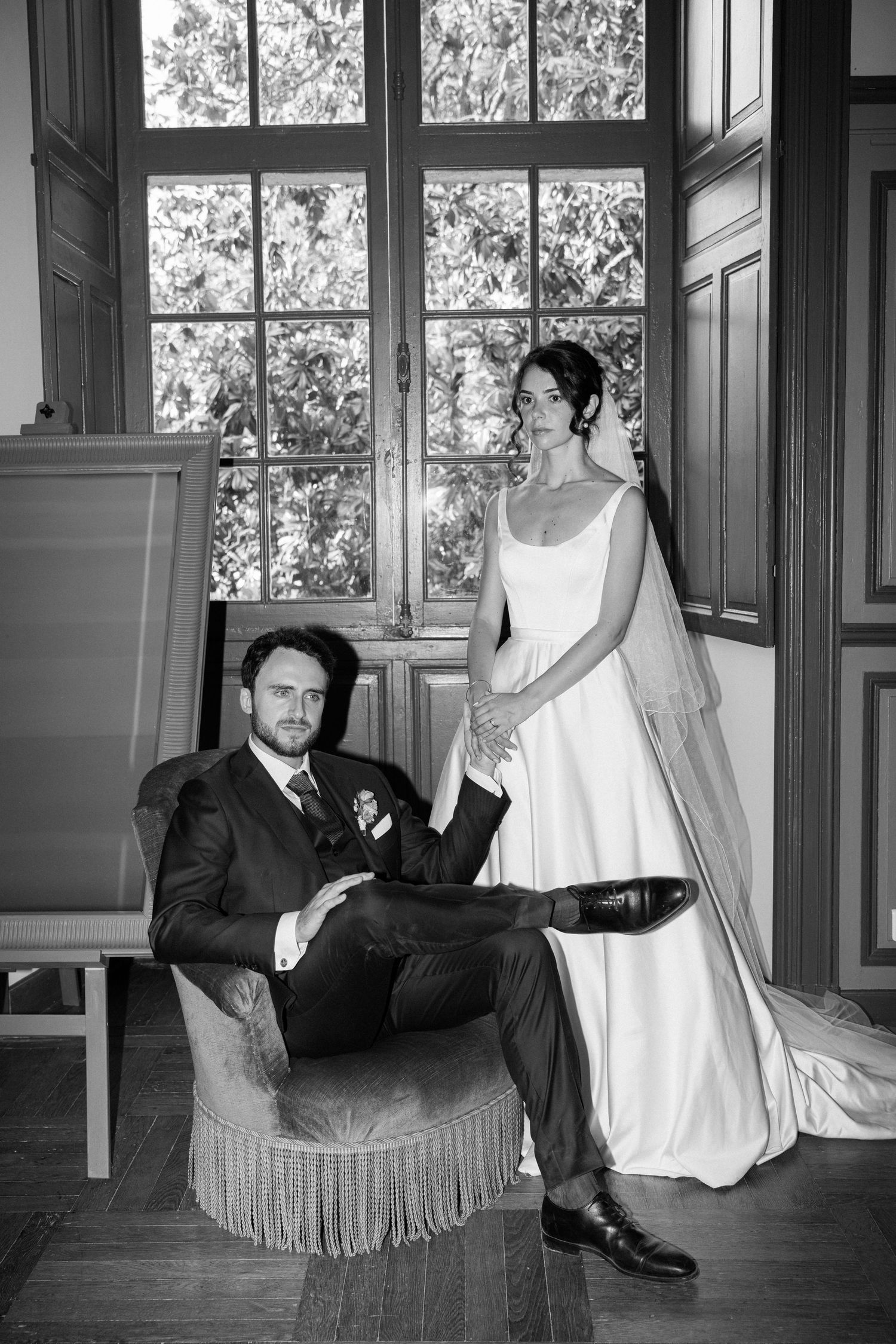 Elegant black and white wedding portrait in a vintage room with large windows.