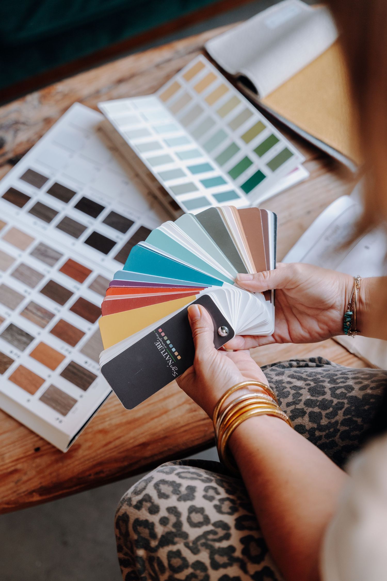 Color swatches and paint samples being reviewed on a wooden surface.
